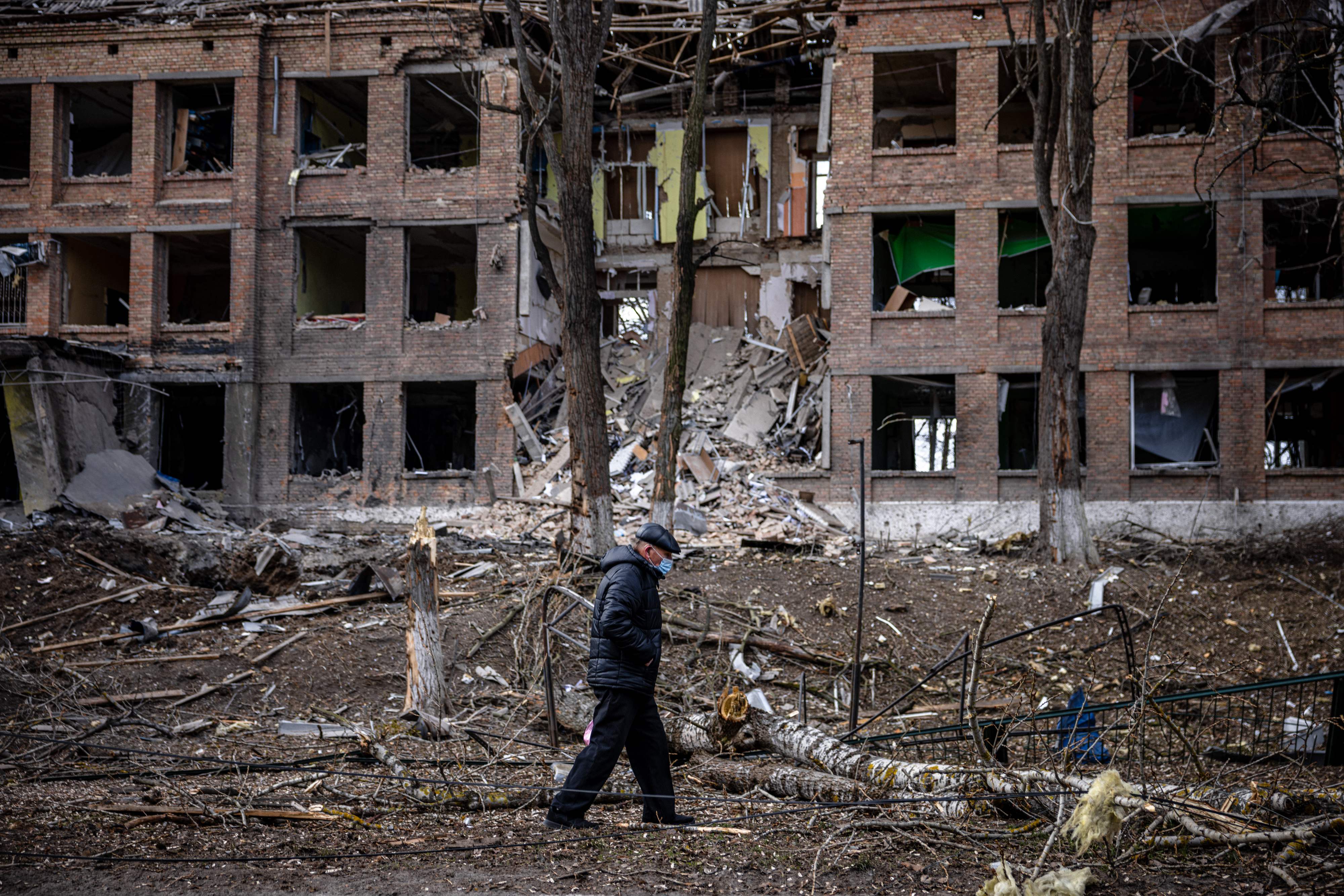 A man walks in front of a destroyed building after a Russian missile attack in the town of Vasylkiv, near Kyiv, on February 27, 2022. - Ukraine's foreign minister said on February 27, that Kyiv would not buckle at talks with Russia over its invasion, accusing President Vladimir Putin of seeking to increase "pressure" by ordering his nuclear forces on high alert. (Photo by Dimitar DILKOFF / AFP)