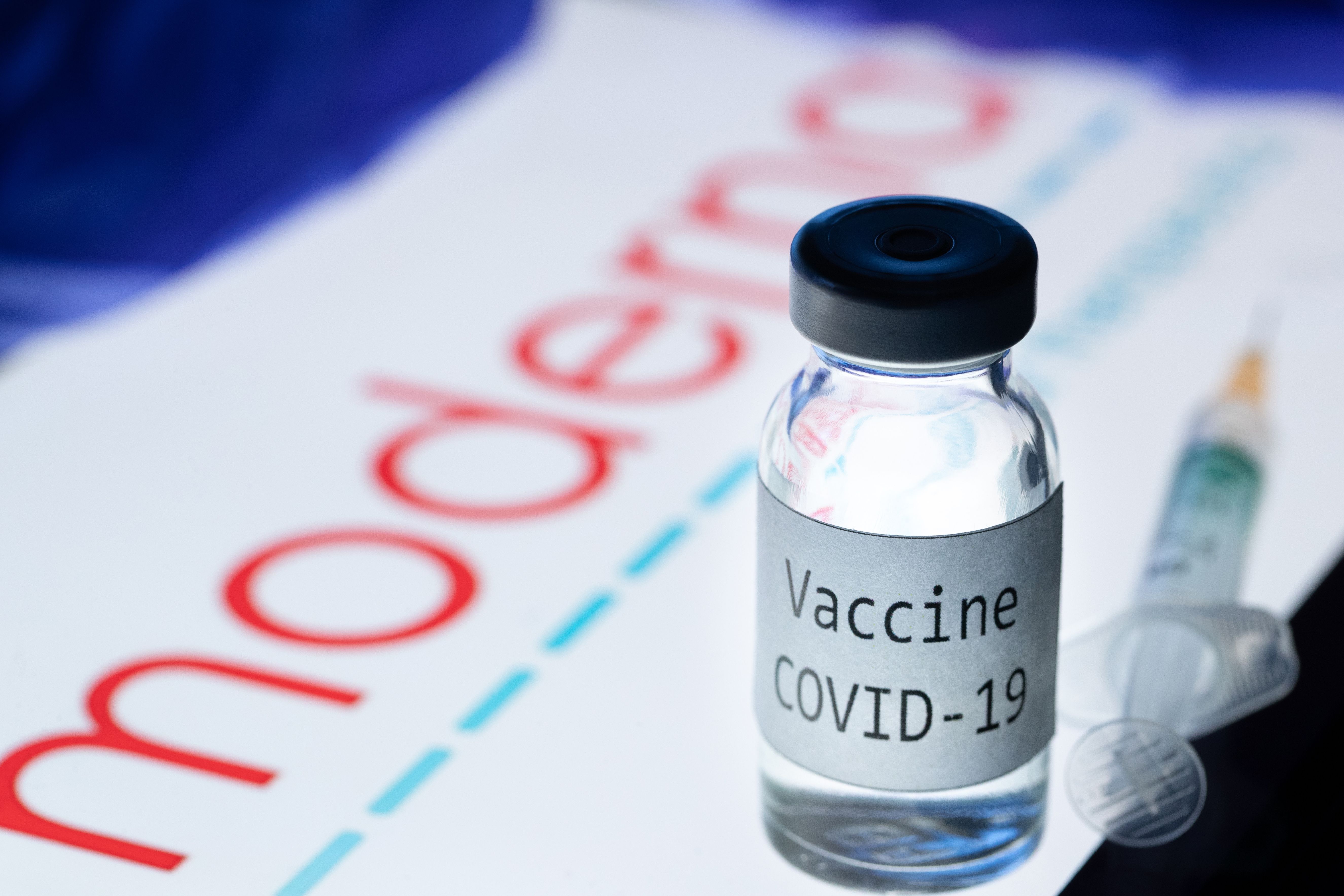 This picture taken on November 18, 2020 shows a syringe and a bottle reading "Vaccine Covid-19" next to the Moderna biotech company logo. - The CEO of Moderna warned European countries on November 17 that dragging out negotiations to purchase its promising new Covid-19 vaccine will slow down deliveries, as other nations that have signed deals will get priority. The biotech company Pfizer said the day after that a completed study of its experimental Covid-19 vaccine showed it is 95 percent effective, after Moderna said its own vaccine was 94.5 percent effective, according to a preliminary analysis. (Photo by JOEL SAGET / AFP)