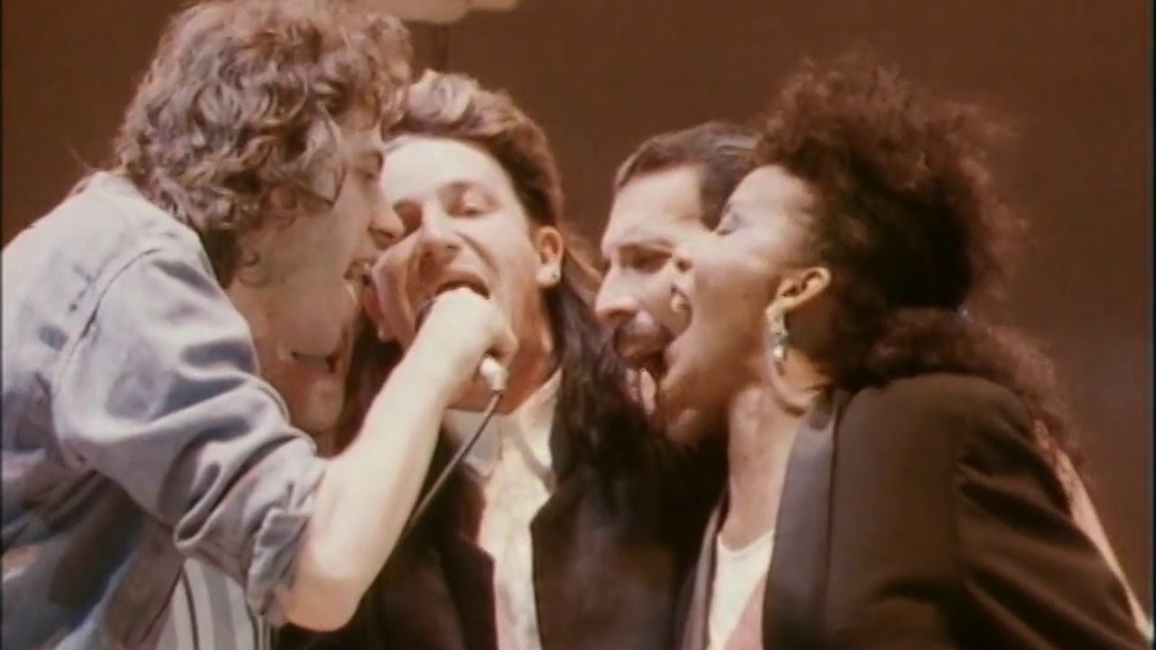 Instante en que Freddy Mercury se acercó al micrófono que compartía Bob Geldof (izquierda) con Bono y Gina Foster. Foto: Captura de Youtube.