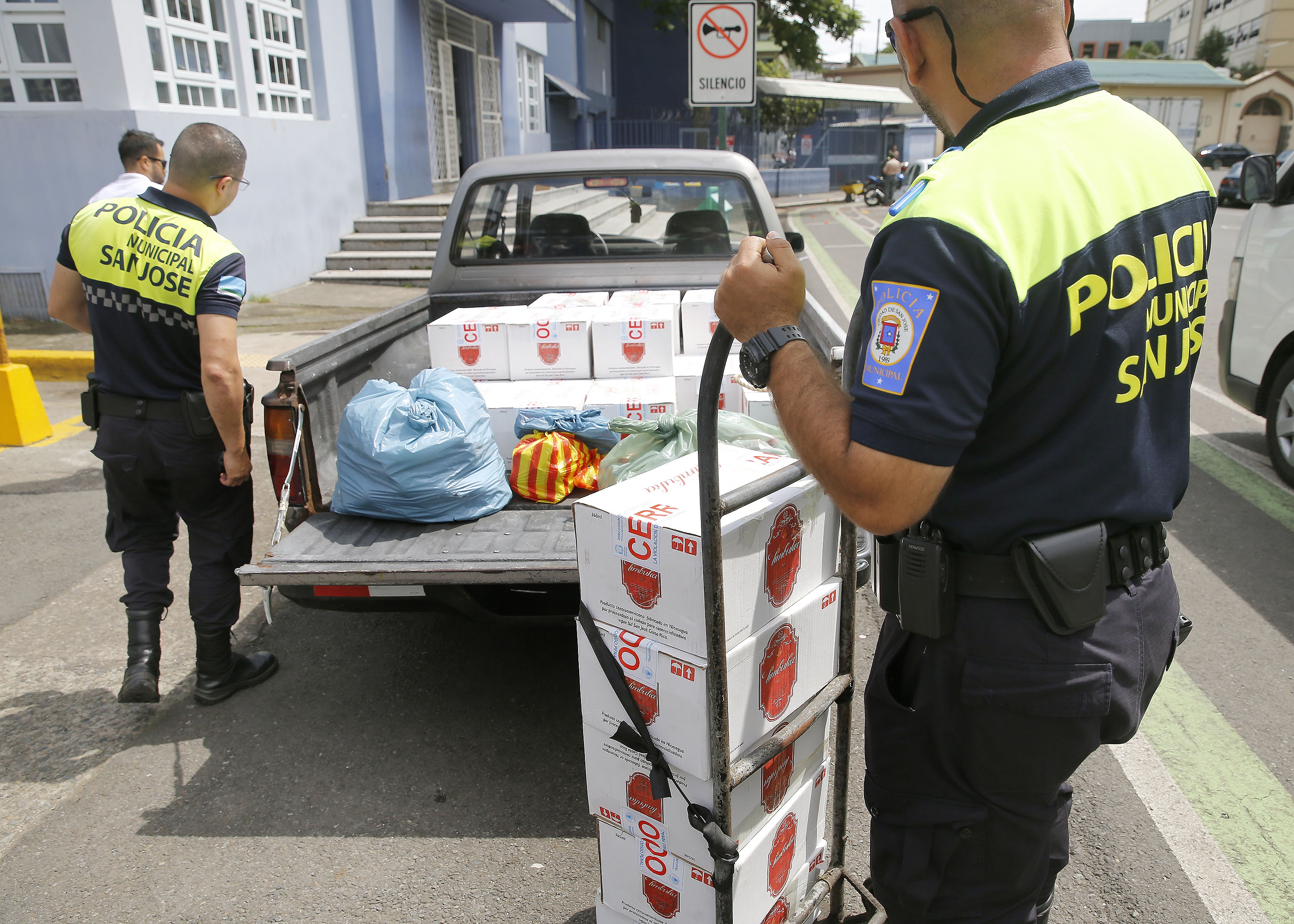 19/07/2019. Ministerio de Salud, San José. Funcionarios de la Municipalidad de San José descargan un decomiso de guaro adulterado frente al edificio del Ministerio de Salud. La acción de la policía municipal se dió la tarde del jueves 18 y el local allanado fue el Comercial Puerto Príncipe ubicado en Avenida 8 y calle 5. Ese producto será almacenado y desechado por autoridades de ese ministerio. En la foto: Luis Zúñiga (lentes) y Benneth Moya fueron los encargados de descargar el decomiso. Foto: Albert Marín.
