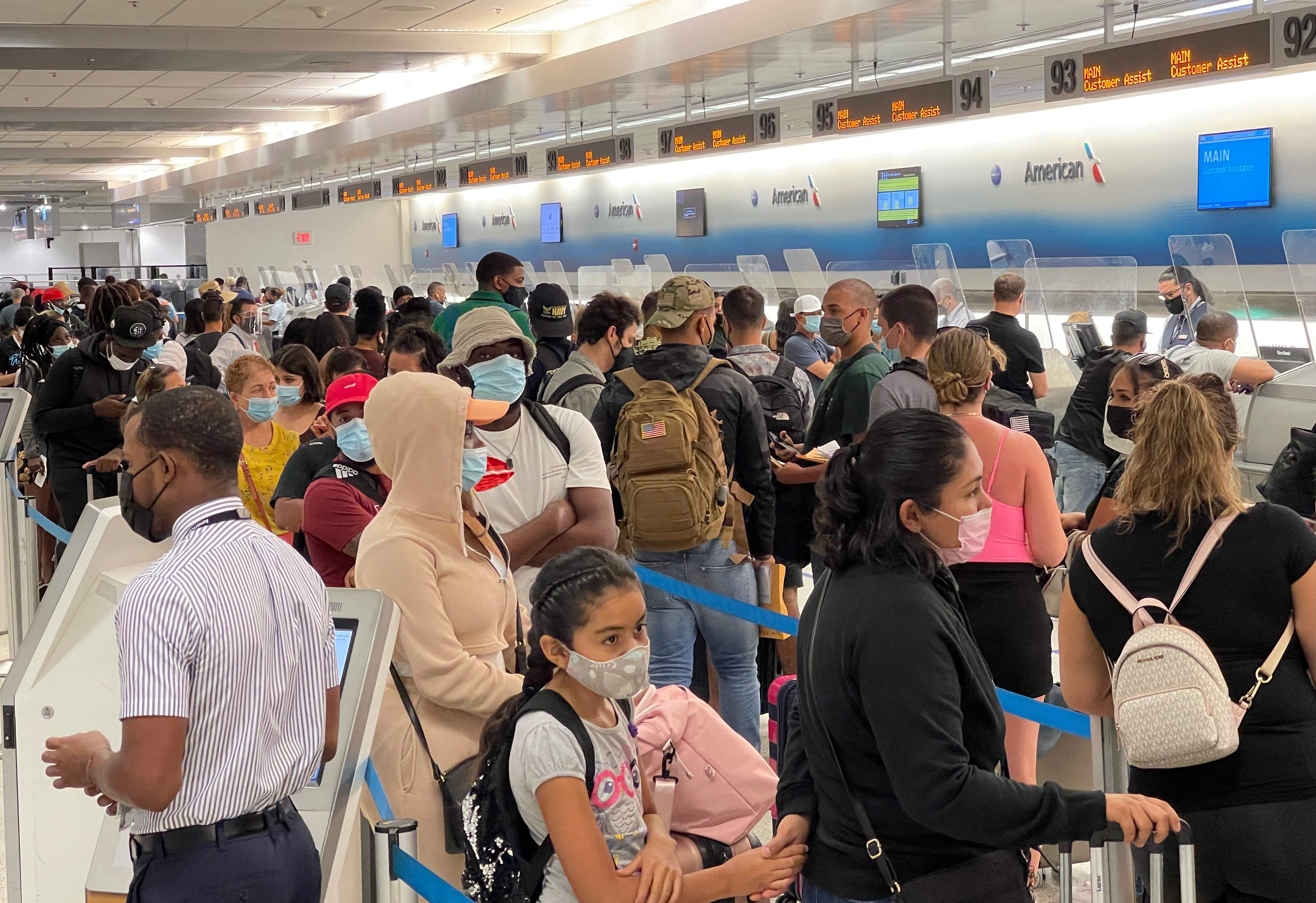 (FILES) In this file photo travellers line up at Miami International Airport (MIA) on August 2, 2021. - The United States announced on September 20, 2021 it will lift Covid travel bans on all passengers in November if they are fully vaccinated and undergo testing and contact tracing. Jeffrey Zients, coronavirus response coordinator for President Joe Biden, told reporters the new "consistent approach" would take effect in "early November." (Photo by Daniel SLIM / AFP)