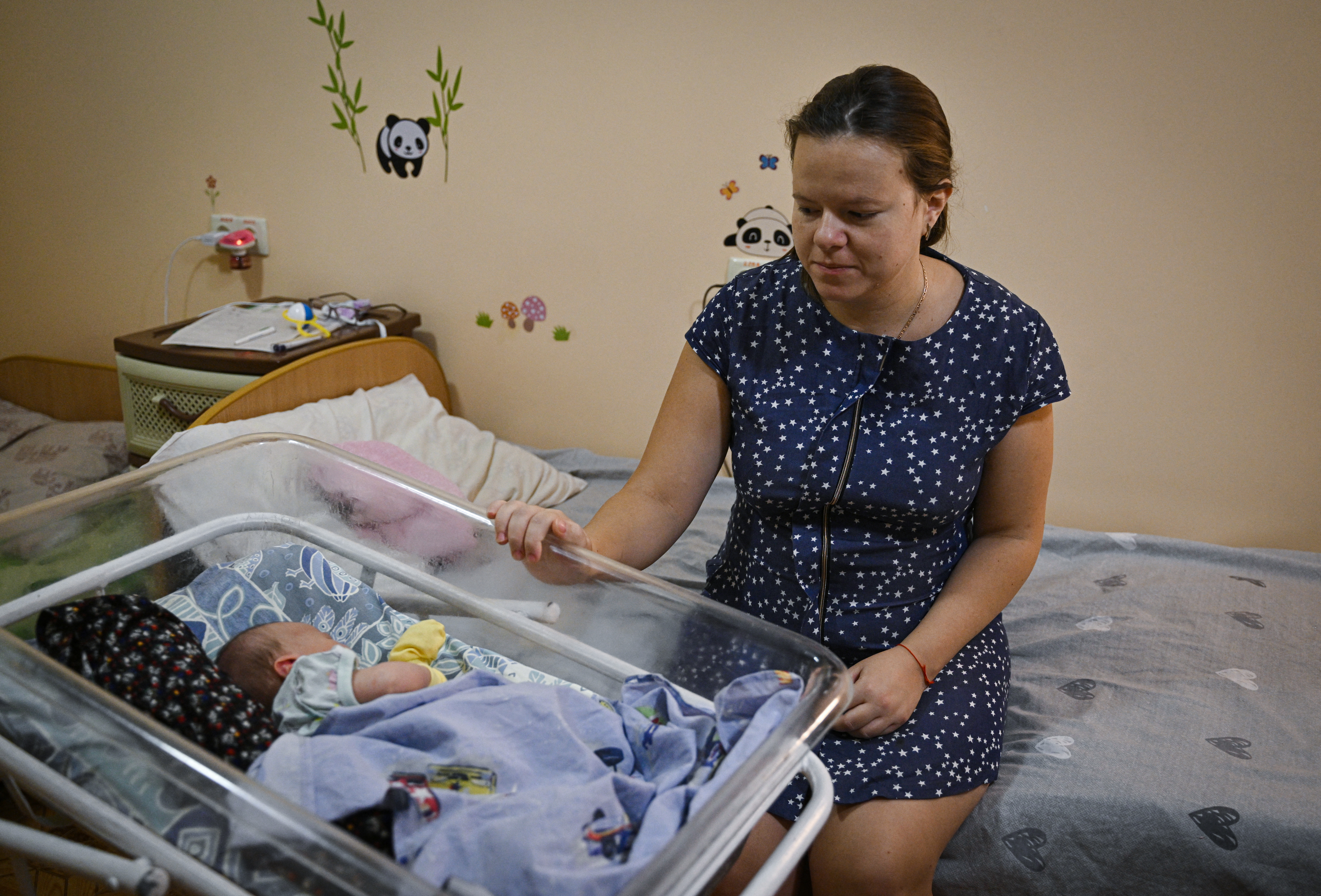 Valentyna, a 25-year-old patient, sits next to her newborn daughter Tetyana, 3-day-old, in a maternity hospital in Zaporizhzhia, a few dozen kilometres from the frontline in Ukraine, on September 1, 2022, amid the Russian invasion of Ukraine. - It is one of the concerns for mothers and expectant mothers at the clinic, who spoke to AFP of their hopes and fears for the future as around five children are born at the hospital every day to both local women and internally displaced people (IDPs) forced to flee from Russian-held areas of the country. After the war began, the hospital set up a shelter in the basement including a room with beds for mothers and cots for newborns. (Photo by Genya SAVILOV / AFP)