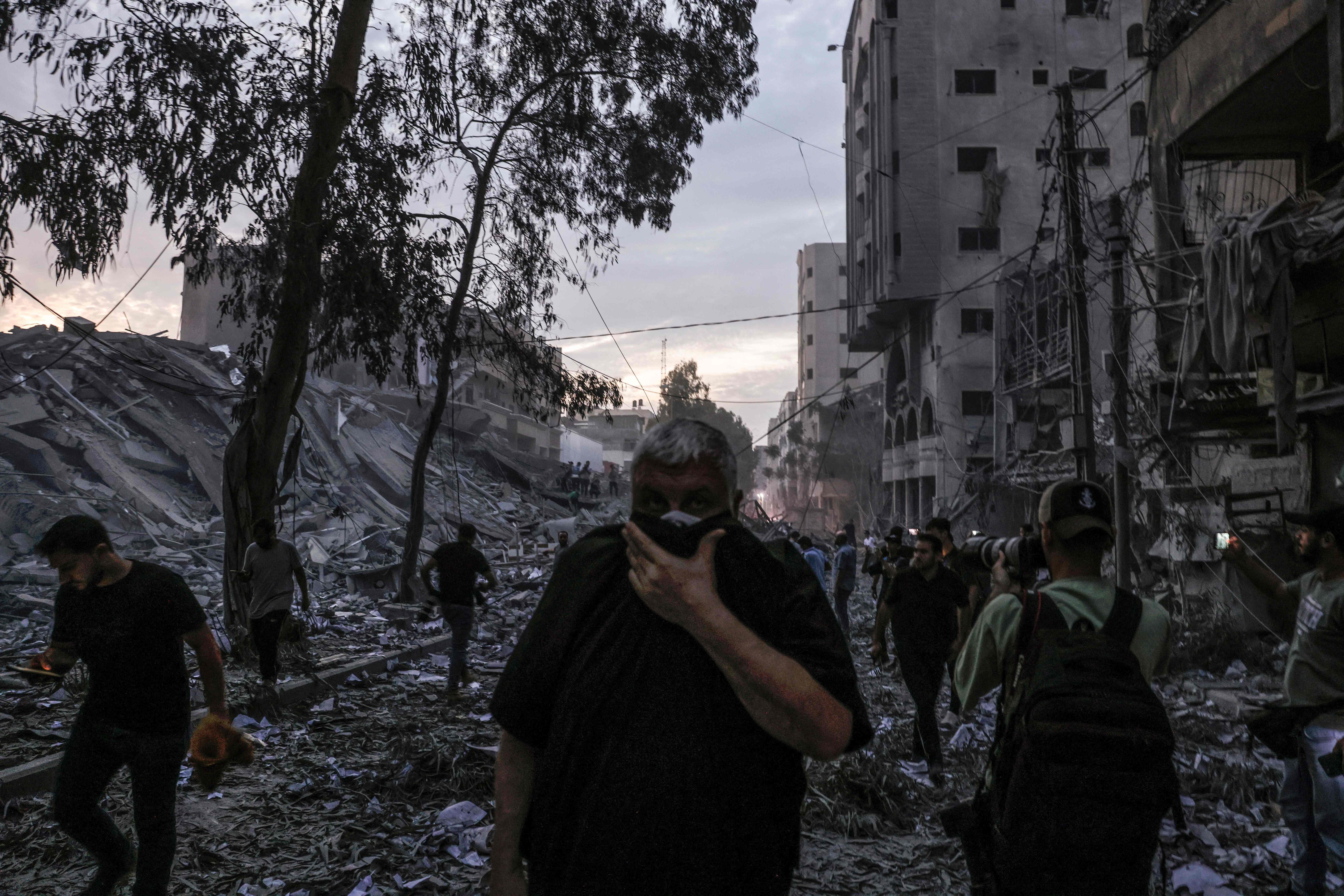 EDITORS NOTE: Graphic content / TOPSHOT - People walk atop the rubble of a tower destroyed in an Israeli air stike in Gaza City on October 7, 2023. Palestinian militants have begun a "war" against Israel which they infiltrated by air, sea and land from the blockaded Gaza Strip, Israeli officials said, a major escalation in the Israeli-Palestinian conflict. (Photo by Mohammed ABED / AFP)