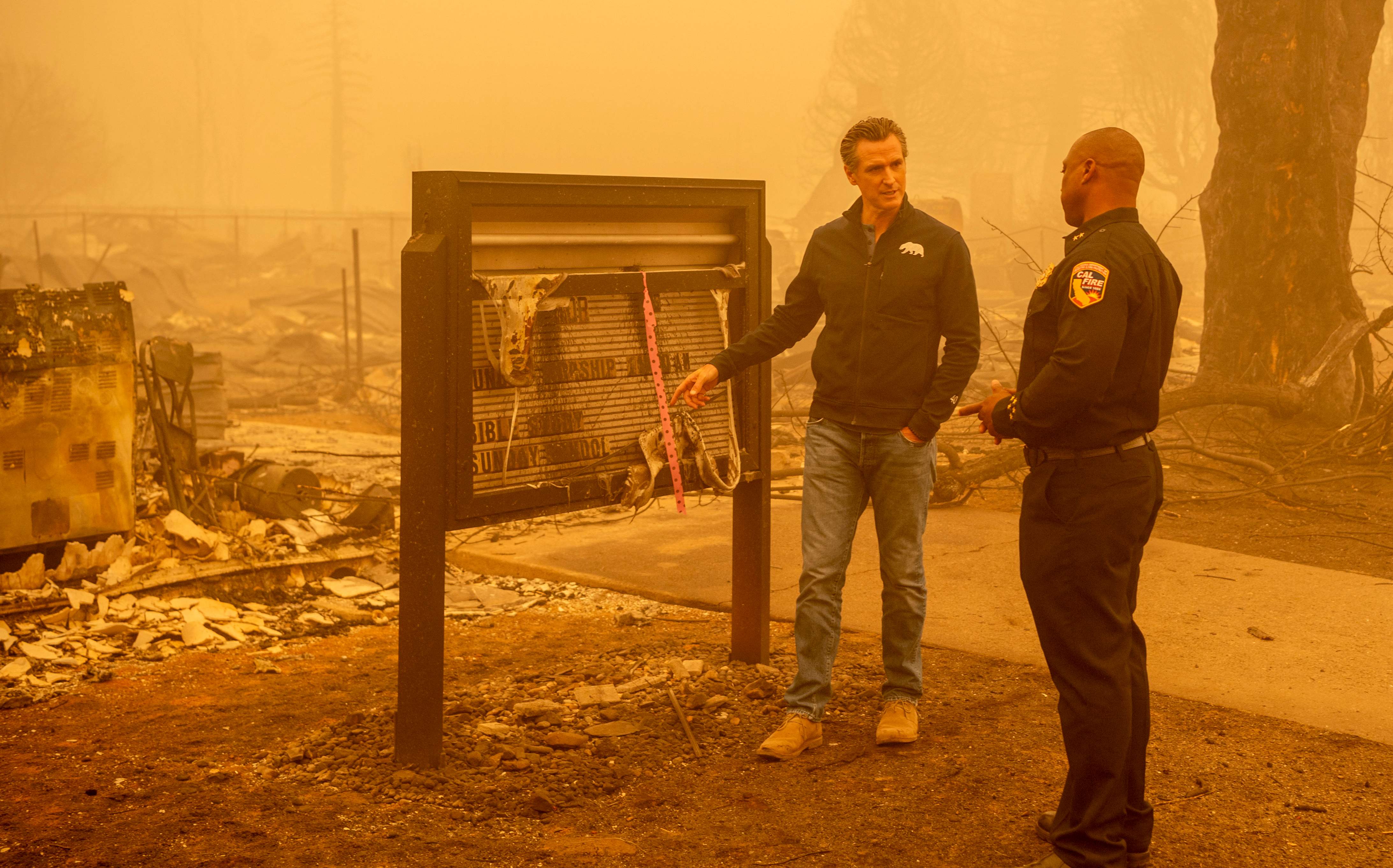 California Governor Gavin Newsom (L) looks at a burned church with Assistant Region Chief for Cal Fire Curtis Brown (R) in downtown Greenville, California on August 7, 2021. - The Dixie fire has now burned more than 430,000 acres and is the largest single fire in California state history. (Photo by JOSH EDELSON / AFP)