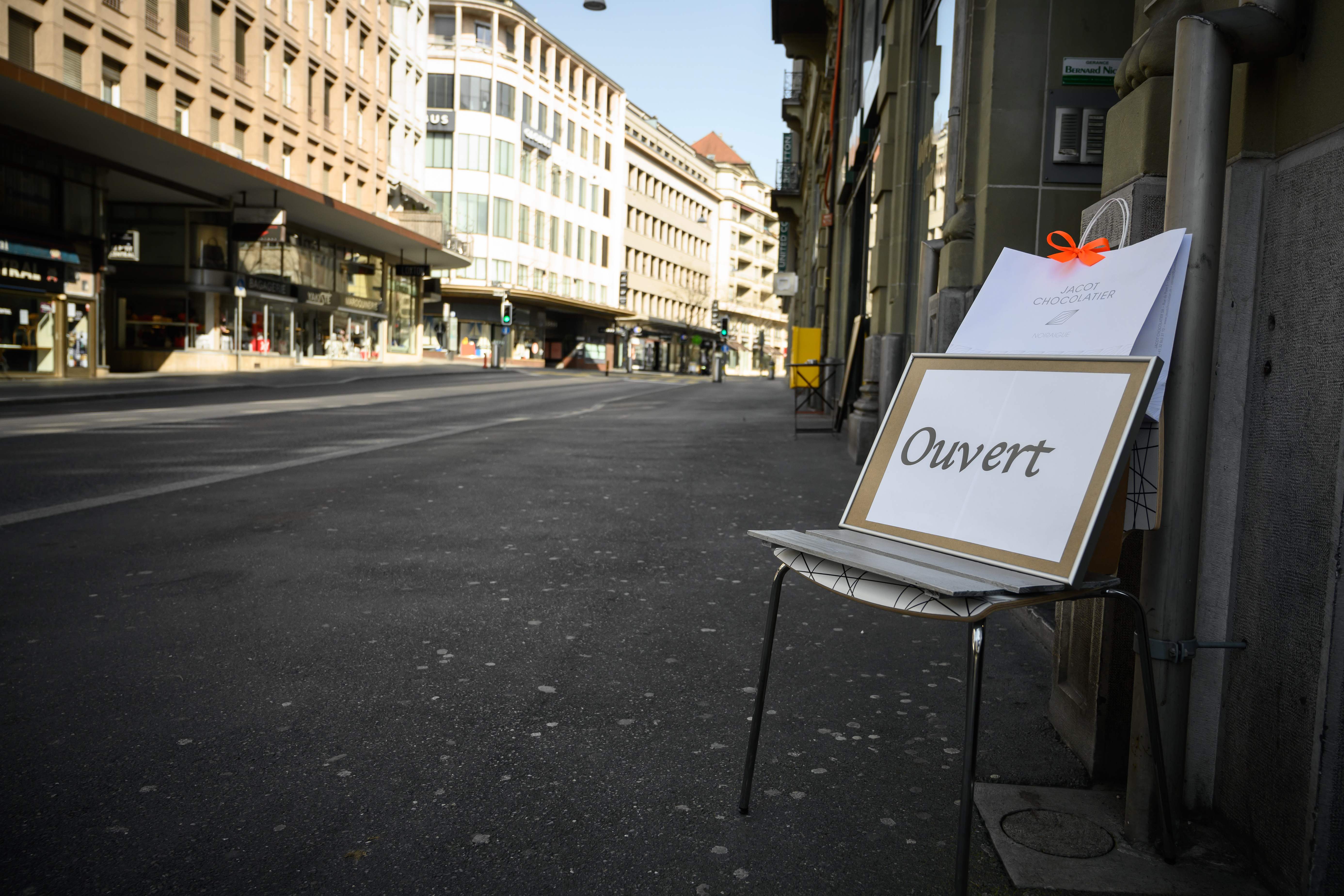 A board reading in French, "Open" is placed on a chair along a deserted street as people stay home amid the spread of the COVID-19 caused by the novel coronavirus, in Lausanne on March 21, 2020. - The Swiss government further tightened measures on March 20, 2020 against COVID-19, but said it would not follow other countries in ordering full confinement, so as not to engage in such a "political show". (Photo by Fabrice COFFRINI / AFP)