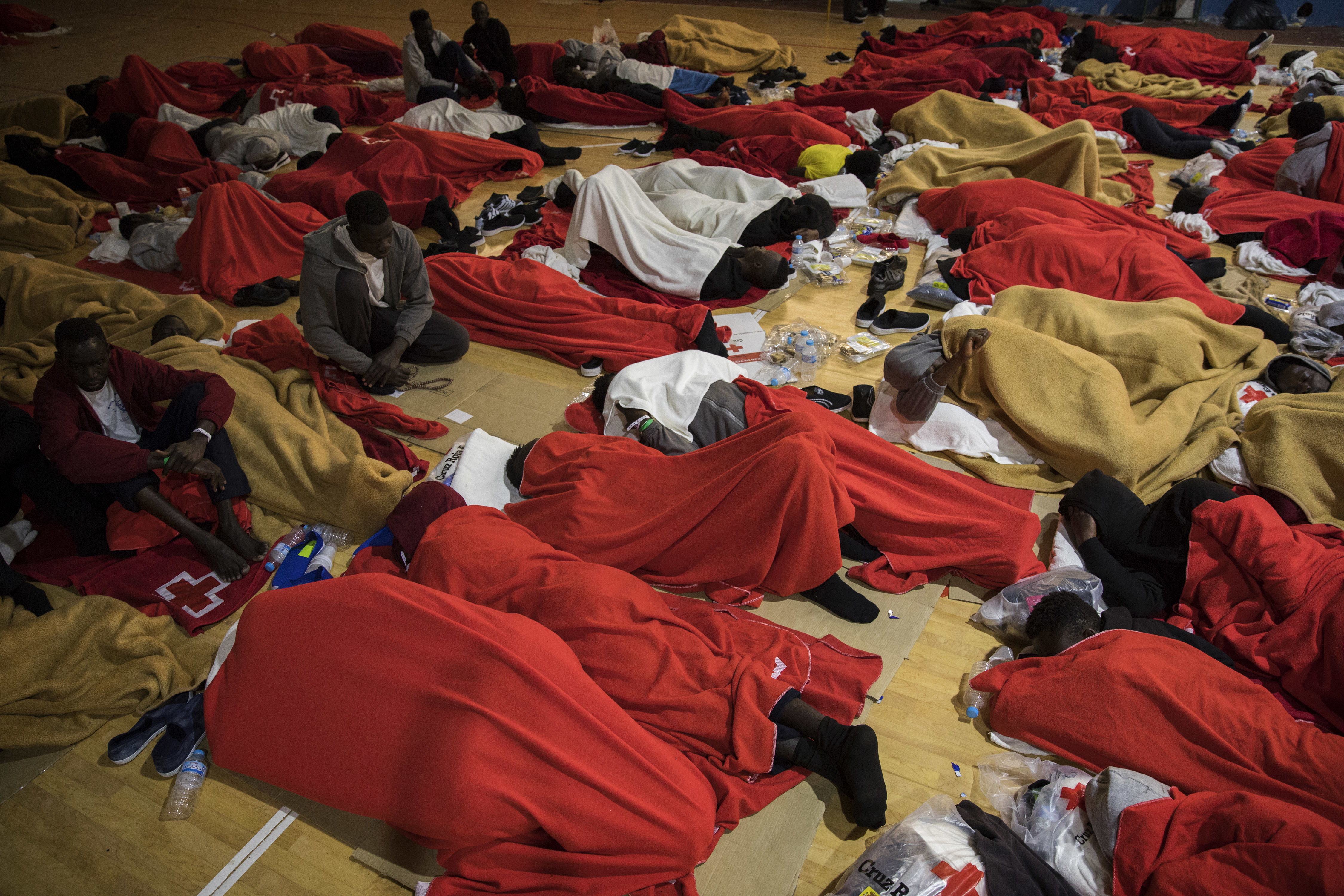 Migrants sleep at a makeshift emergency center at Barbate's municipal sports center, in the south of Spain, Friday, June. 29, 2018, after being rescued by Spain's Maritime Rescue Service in the Strait of Gibraltar. European Union leaders declared victory Friday, claiming to have set aside major differences over how best to handle migrant arrivals as they commissioned new plans to screen people in North Africa for eligibility to enter Europe. (AP Photo/Emilio Morenatti)