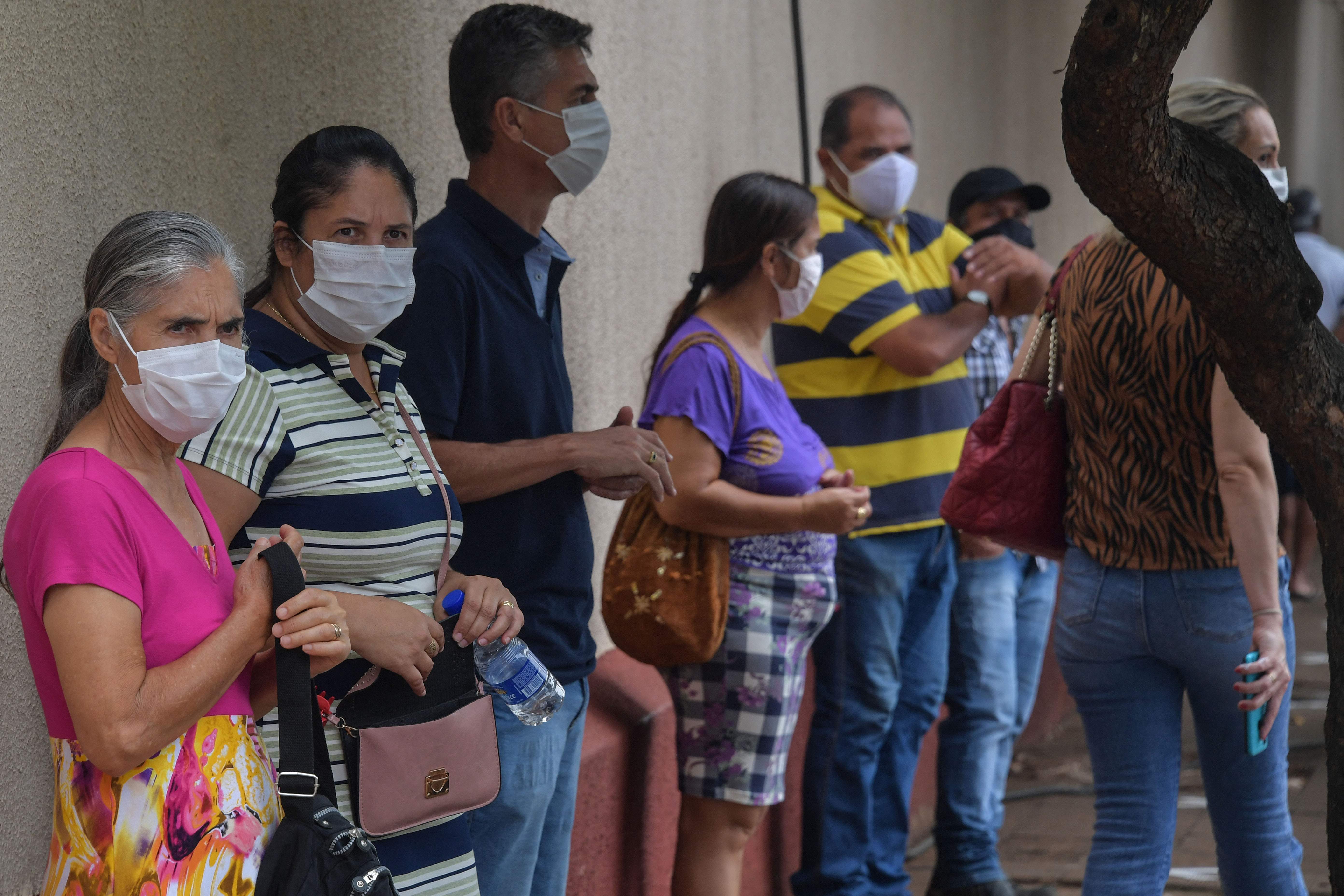 Residents line up to receive the Coronavac vaccine against COVID-19, in Serrano, about 323 km from Sao Paulo, Brazil, on February 17, 2021. - A small town in the interior of the Brazilian state of Sao Paulo began vaccinating its entire adult population on Wednesday as part of an unprecedented clinical study to analyse the impact of immunisation in controlling the Covid-19 pandemic. (Photo by NELSON ALMEIDA / AFP)