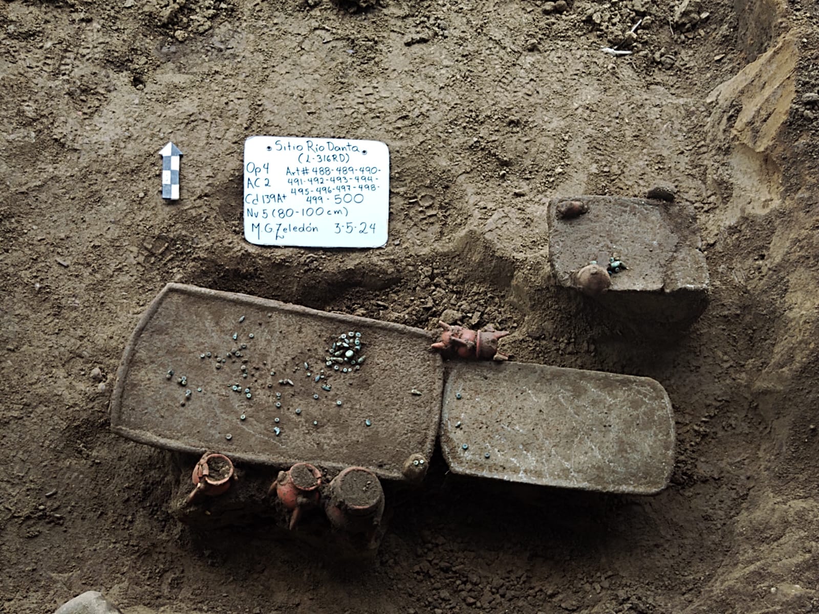 Metates, vasijas y piezas de joyería en un sitio funerario.
