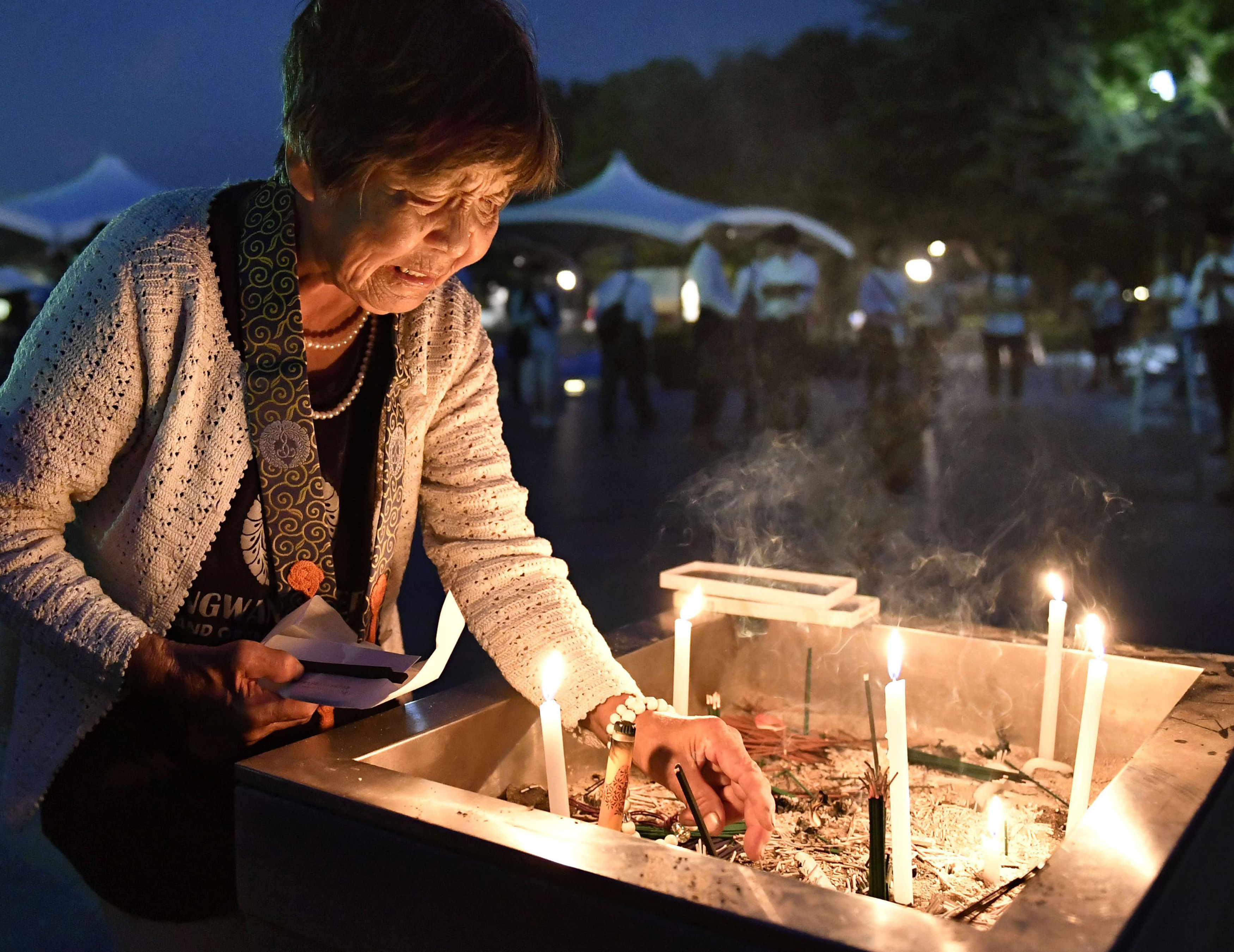 Una mujer enciende una vela mientras se reza por las víctimas de la bomba atómica en el Parque Memoria de la Paz de Hiroshima, en Hiroshima, al oeste de Japón, la madrugada del sábado en el marcó del 71 aniversario del bombardeo atómico sobre Hiroshima.