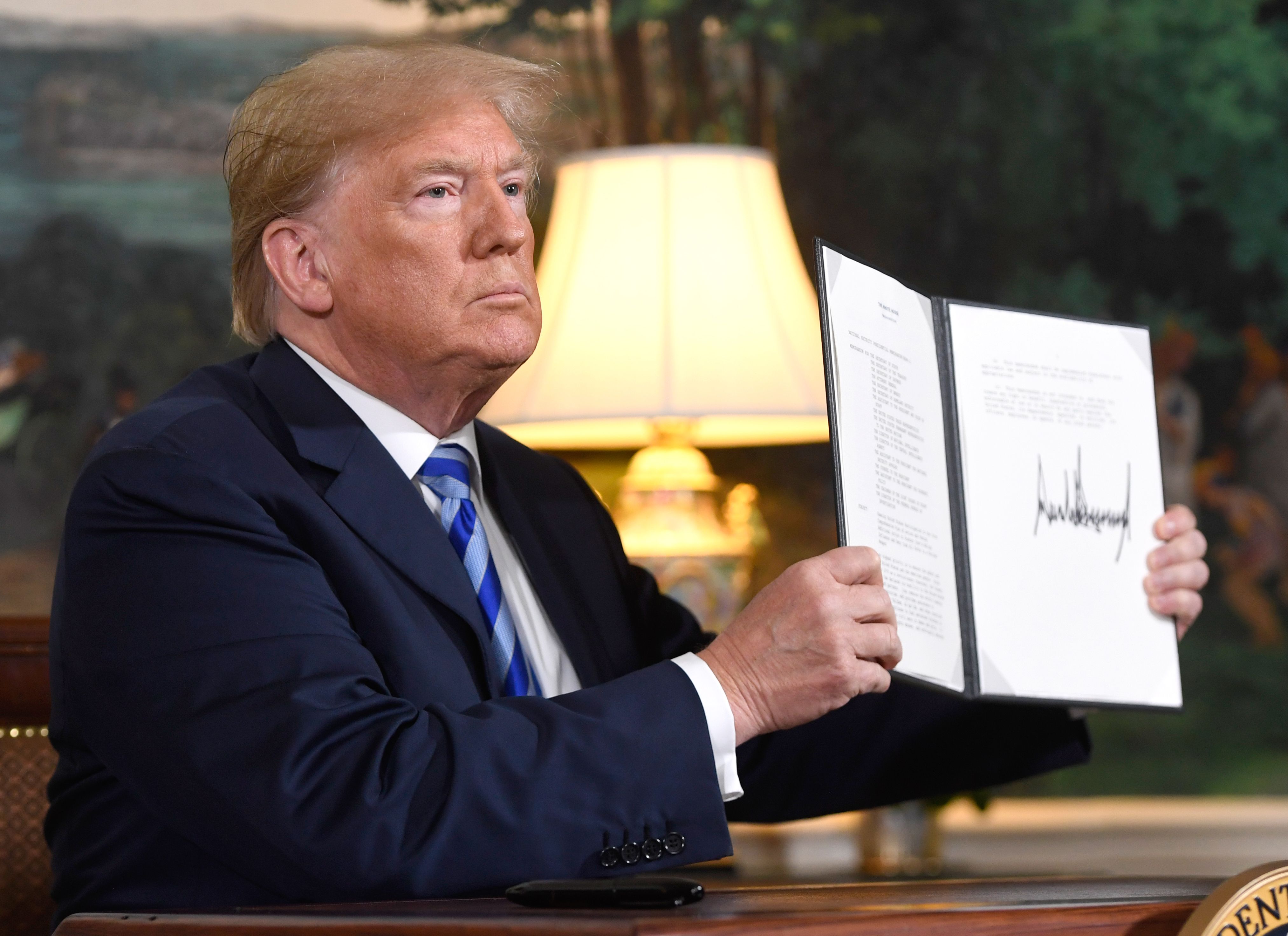 US President Donald Trump signs a document reinstating sanctions against Iran after announcing the US withdrawal from the Iran Nuclear deal, in the Diplomatic Reception Room at the White House in Washington, DC, on May 8, 2018. / AFP PHOTO / SAUL LOEB