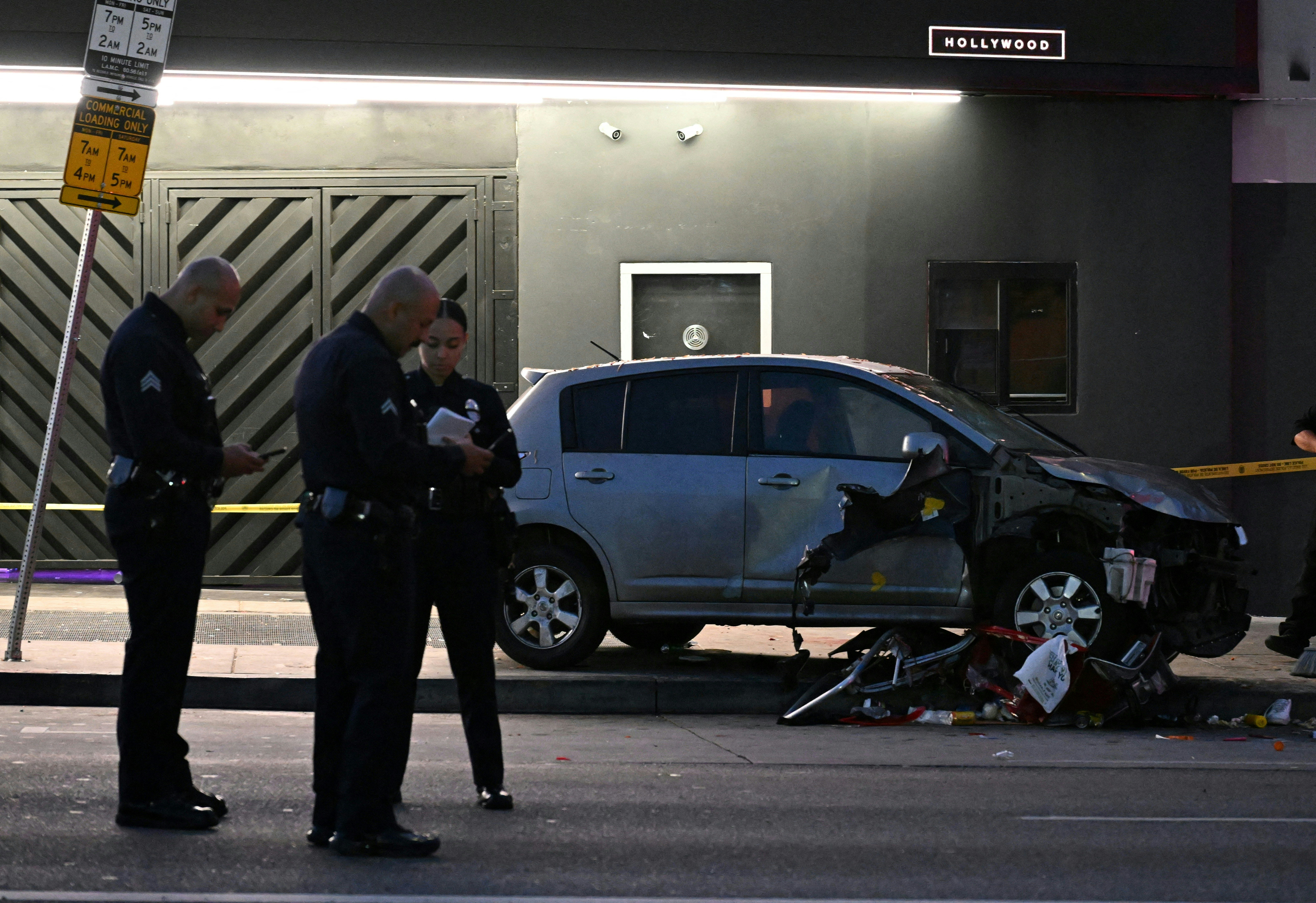Oficiales permanecen en la escena de un vehículo que se estrelló tras atropellar a una multitud en Hollywood durante la madrugada del 19 de julio de 2025, dejando 28 personas heridas, según informó el Departamento de Bomberos de Los Ángeles. Más de 100 bomberos acudieron al sitio en East Hollywood y atendieron a tres pacientes en estado crítico, seis en condición grave y 19 en condición estable, indicó la institución. (Foto: Robyn Beck / AFP)