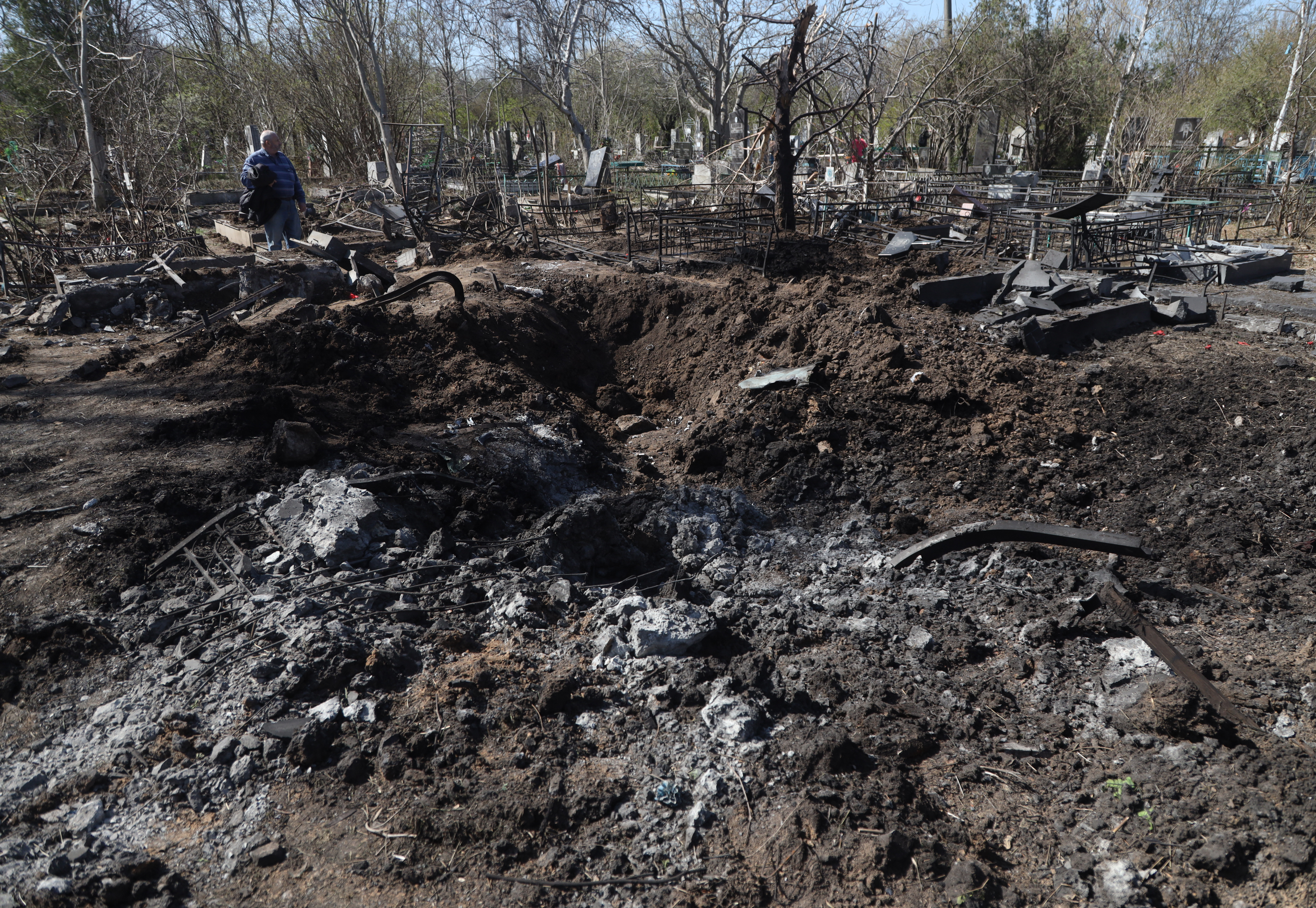 A local resident looks at damaged graves in a cemetery of Odessa, southern Ukraine, on April 24, 2022, which was reportedly hit by missile on April 23, 2022. (Photo by Oleksandr GIMANOV / AFP)