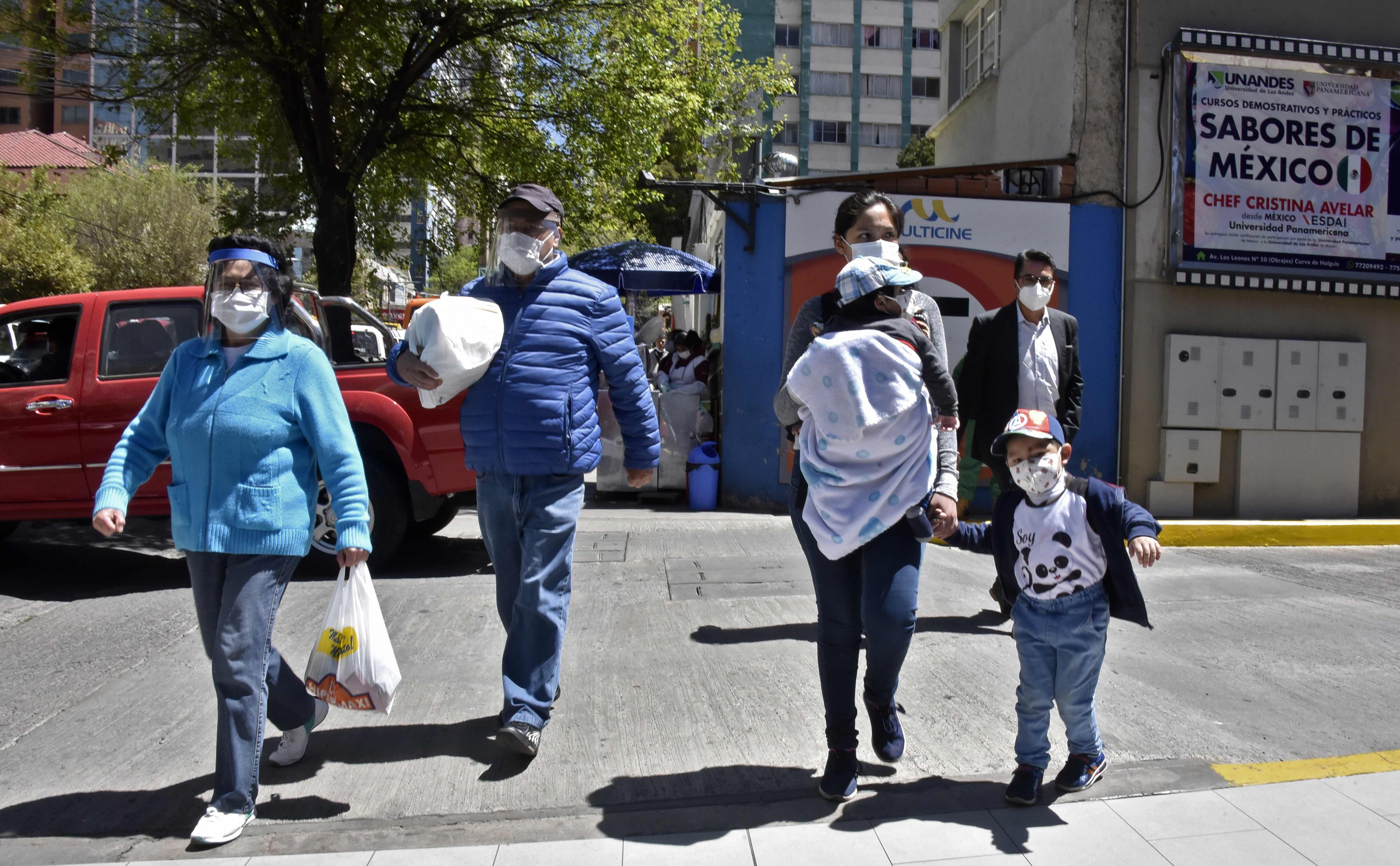 People wear face masks while crossing a street in La Paz, on September 29, 2020, amid the COVID-19 pandemic. - General elections will take place in Bolivia on October 18 amid the new coronavirus pandemic. (Photo by AIZAR RALDES / AFP)