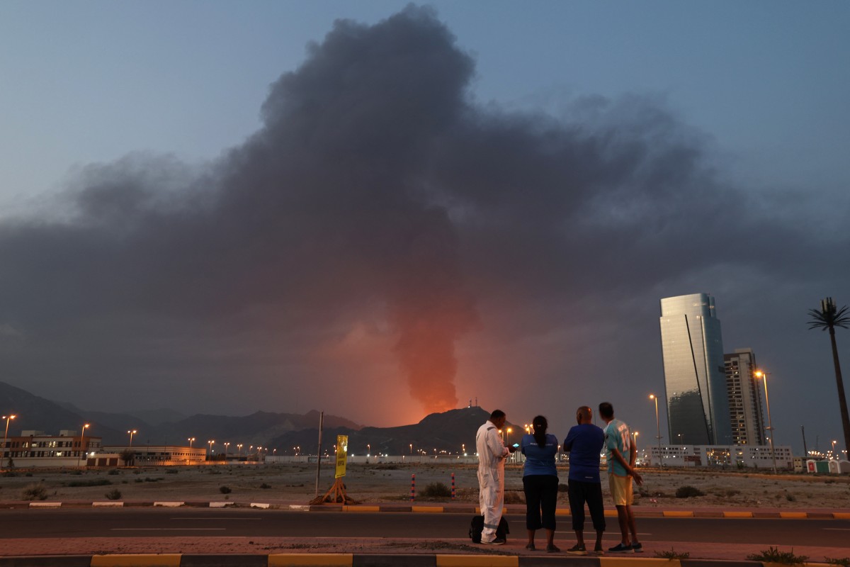 Trabajadores extranjeros observan una densa columna de humo negro que se eleva tras una explosión en la zona industrial de Fujairah, el 3 de marzo de 2026.