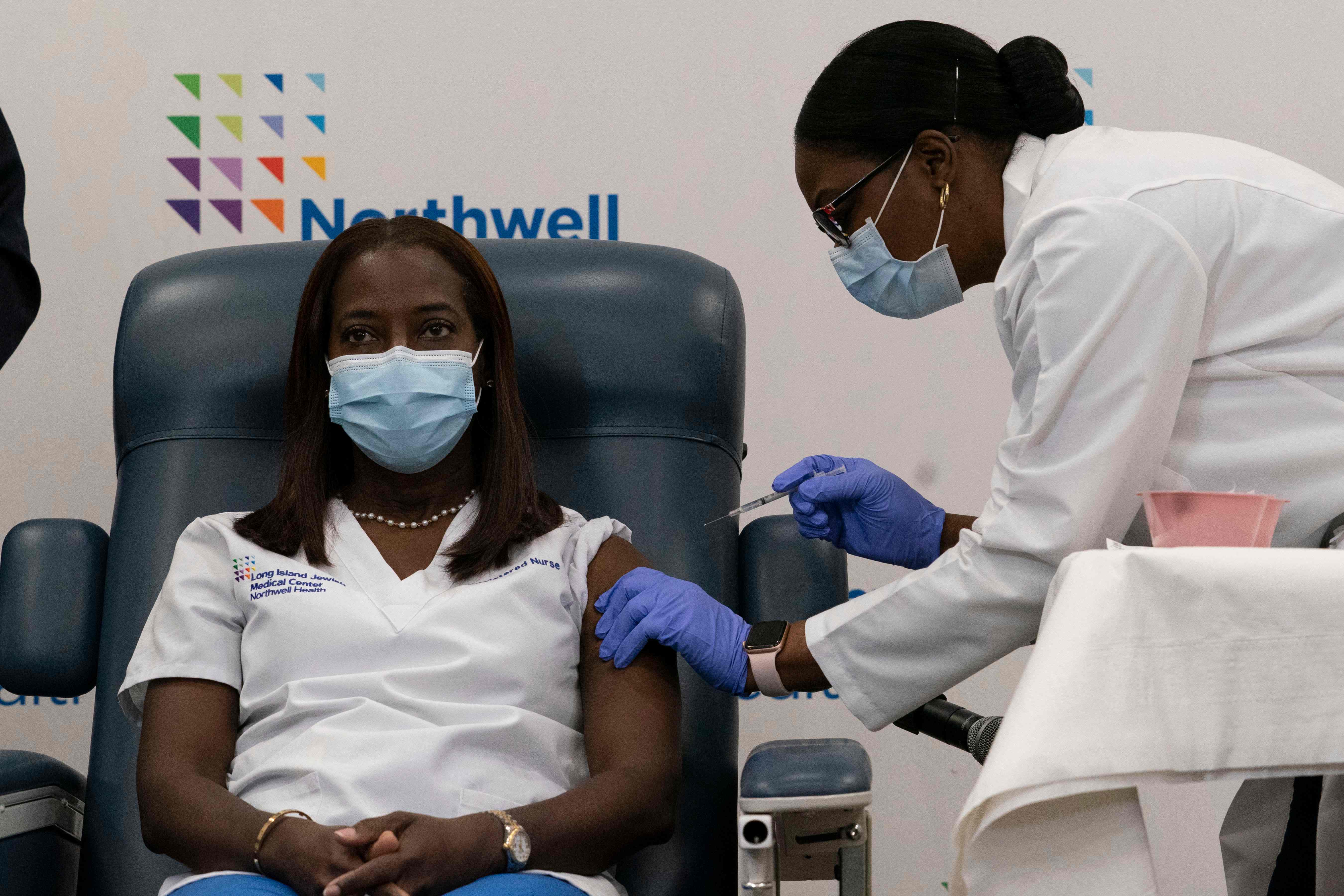 Sandra Lindsay(L), a nurse at Long Island Jewish Medical Center, is inoculated with the COVID-19 vaccine by Dr. Michelle Chester, at Long Island Jewish Medical Center, on December 14, 2020 in the Queens borough of New York. - The rollout of the Pfizer and BioNTech vaccine, the first to be approved by the Food and Drug Administration, ushers in the biggest vaccination effort in US history. More than 299,000 Americans have been killed by the virus, including over 35,000 residents of New York state. (Photo by Mark Lennihan / POOL / AFP)