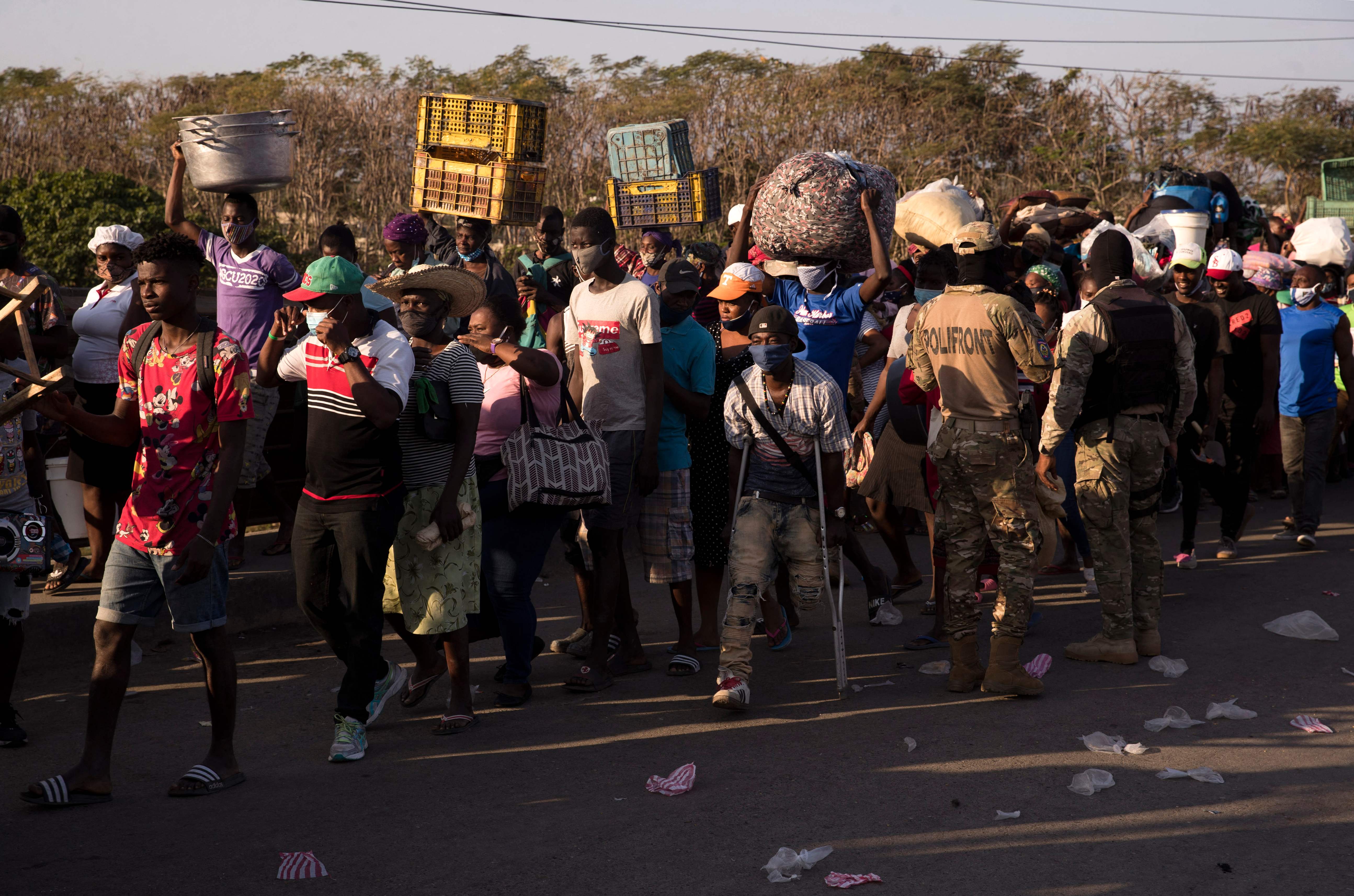 (FILES) In this file photo Dominican military agents control the passage of Haitian nationals from Ouanaminthe, Haiti, to Dajabon, Dominican Republic, after opening the gate on the bridge over the bordering Massacre River, on March 5, 2021. - The government of the Dominican Republic on July 7, 2021 ordered the "immediate closure" of its border with Haiti after the assassination of the president of the neighboring country, Jovenel Moise. The border closure was effective immediately, the communications officer of the defense ministry, Ceinett Sanchez, told AFP. (Photo by Erika SANTELICES / AFP)