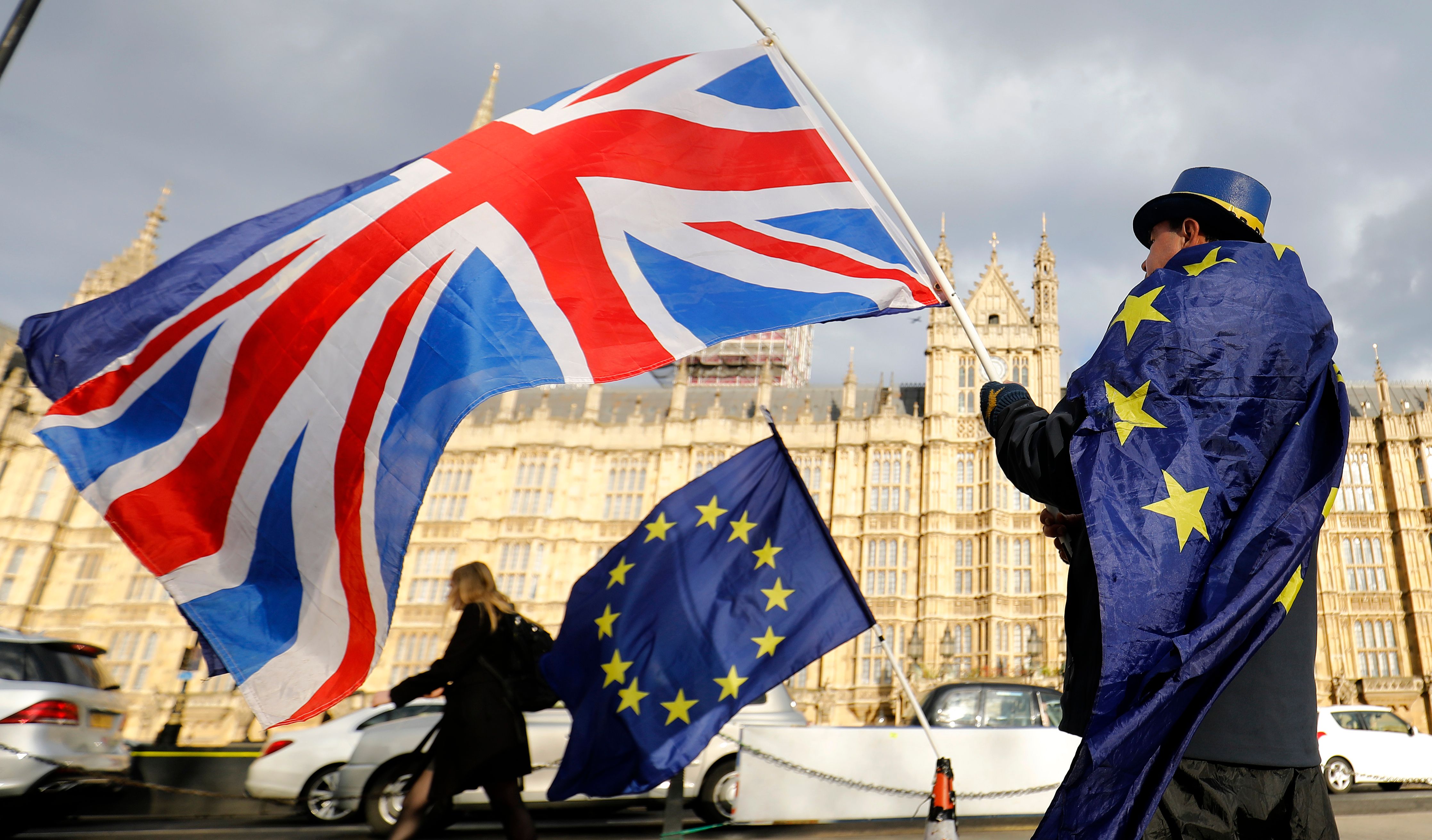 (FILES) In this file photo taken on March 28, 2018 an anti-Brexit demonstrator waves a Union flag alongside a European Union flag outside the Houses of Parliament in London. - The EU and Britain agreed on November 22, 2018, a draft declaration on their post-Brexit relations that sets out an "ambitious, broad, deep and flexible partnership," officials said. European Council President Donald Tusk said the EU executive informed him it has agreed the political declaration on the future relationship with Britain. (Photo by Tolga AKMEN / AFP)