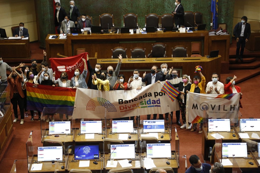Members of different social movements celebrate in the Senate after the passing of a bill to legalize same-sex marriage in Chile, at the National Congress in Valparaiso, Chile, on December 7, 2021. - Chile's congress on Tuesday approved a long-awaited bill to legalize same-sex marriage, joining just a handful of countries in majority Catholic Latin America with similar laws. The measure has the support of President Sebastian Pinera, who must sign it into law, and will also enable married same-sex couples to adopt children. (Photo by Dedvi MISSENE / AFP)