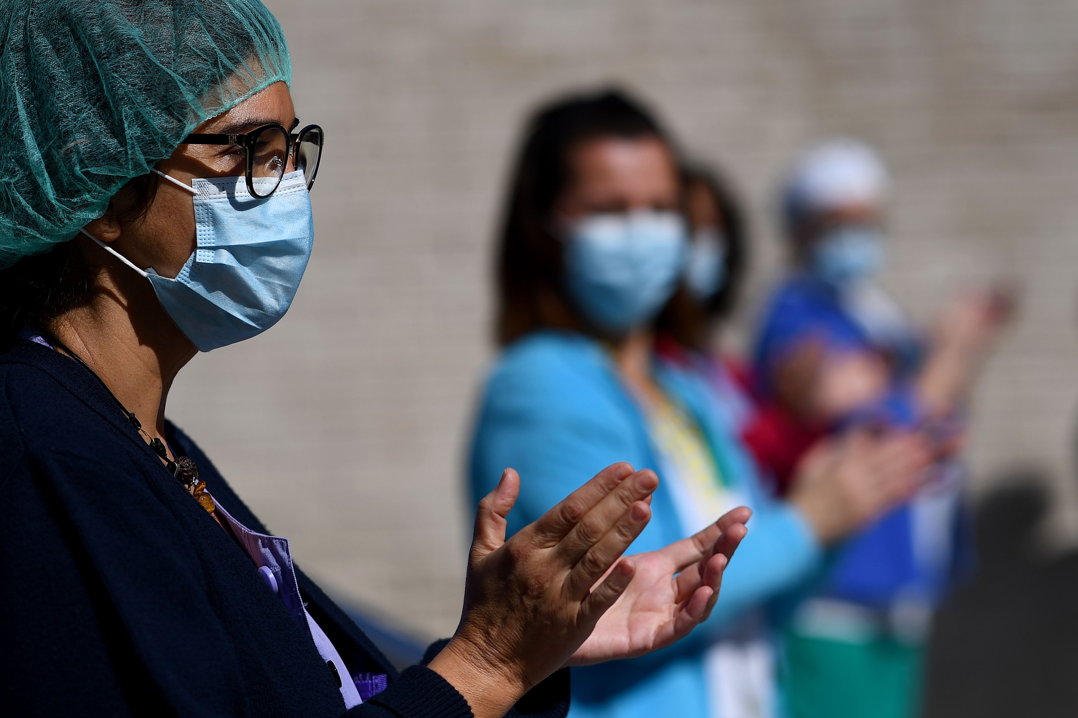Health workers of the Gregorio Maranon Hospital applaud to pay tribute to cleaning workers in Madrid on April 2, 2020 amid a national lockdown to fight the spread of the COVID-19 coronavirus. - The coronavirus death toll in Spain surged past 10,000 after a record 950 deaths in 24 hours, with the number of confirmed cases passing the 110,000 mark, the government said. (Photo by GABRIEL BOUYS / AFP)
