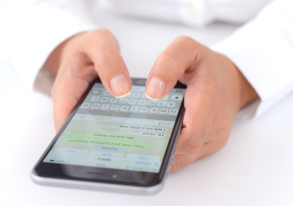 ?stanbul, Turkey - July 14, 2015: Hands holding a iPhone 6 Plus displaying WhatsApp messaging application. iPhone is a touchscreen smart phone produced by Apple Inc.