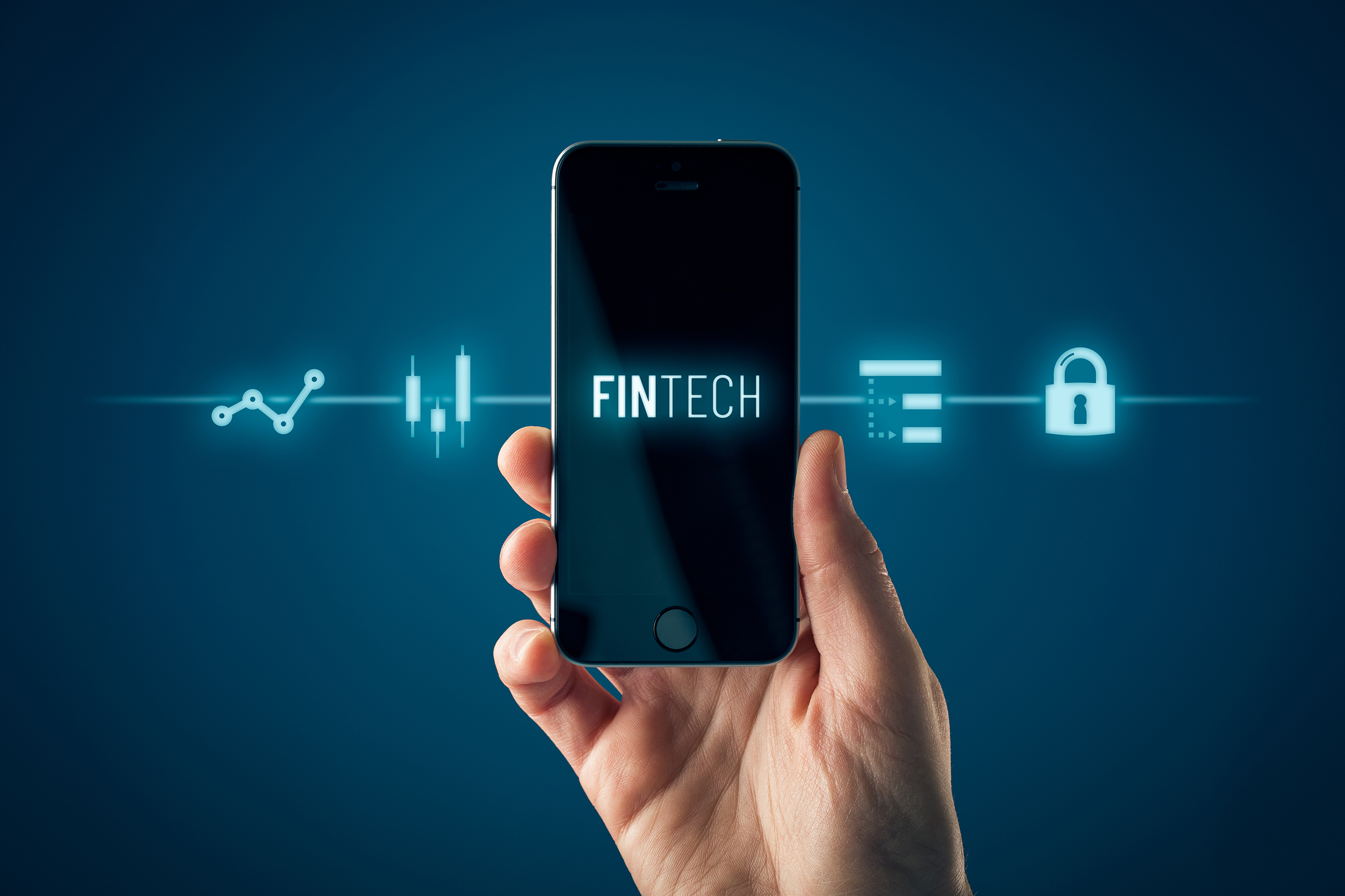 Una mano sostiene un teléfono móvil con la palabra "Fintech" en la pantalla, rodeada de iconos tecnológicos relacionados con finanzas, como gráficos y un candado, representando las innovaciones en el sector financiero.