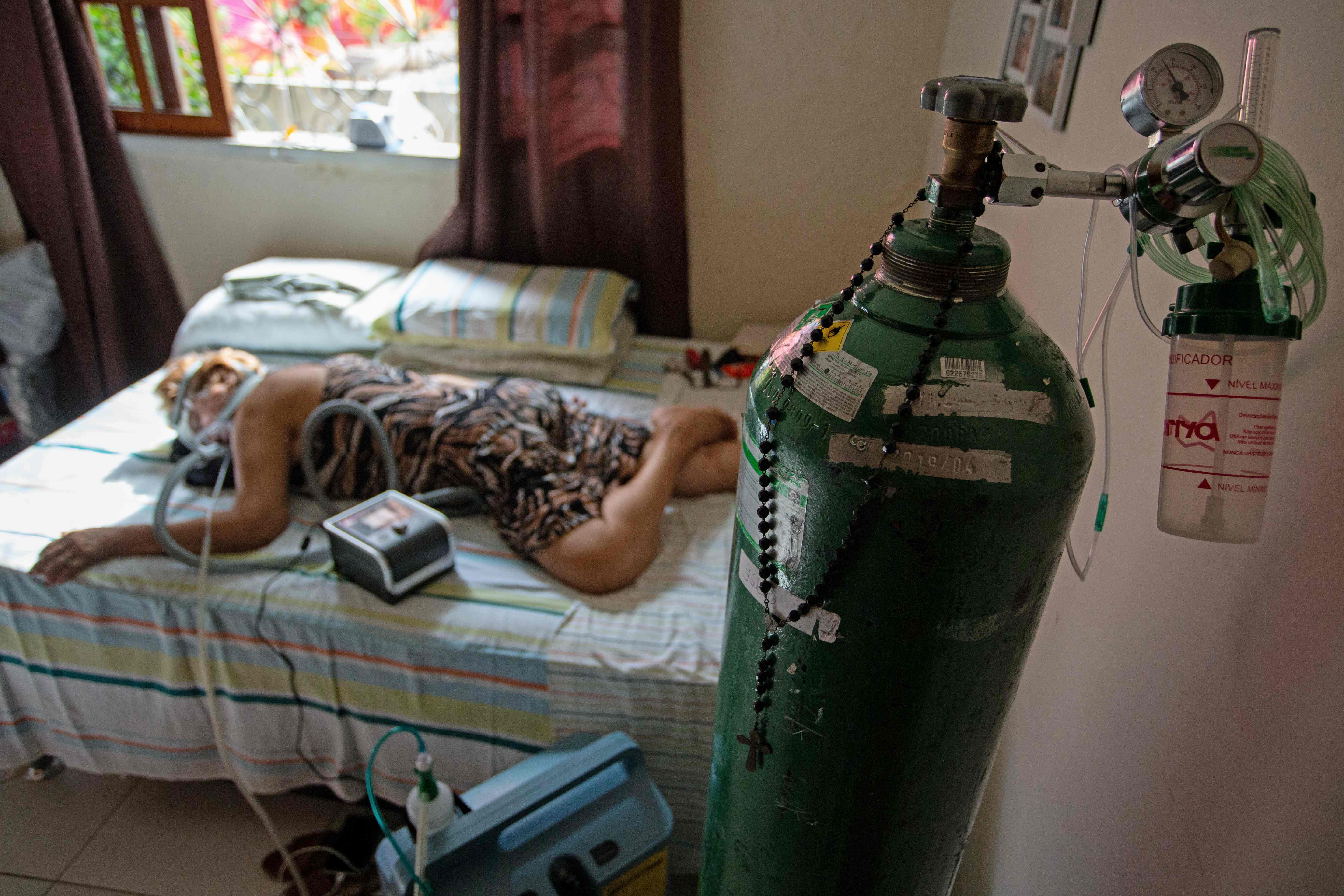 TOPSHOT - Dilza Maria Pereira Rodrigues, 71, receives treatment for COVID-19 at her home after 15 days of treatment at the hospital in Manaus, Brazil on January 2, 2021. - As a new pandemic wave hits Latin America, the region with the second highest number of deaths from COVID-19 in the world, the same scene of desperation repeats itself: people queueing in long lines or paying exorbitant prices for an oxygen tank, while the sick die of asphyxiation in hospitals. (Photo by MICHAEL DANTAS / AFP)