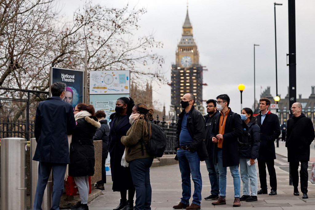 Members of the public queue onto Westminster Bridge, near the Houses of Parliament, as they wait to receive a dose of a Covid-19 vaccine at a coronavirus vaccination centre outside Guy's and St Thomas' Hospital in central London on December 13, 2021. - UK Prime Minister Boris Johnson on Monday said at least one person infected with Omicron had died, as the country began an ambitious booster programme against the variant. (Photo by Tolga Akmen / AFP)
