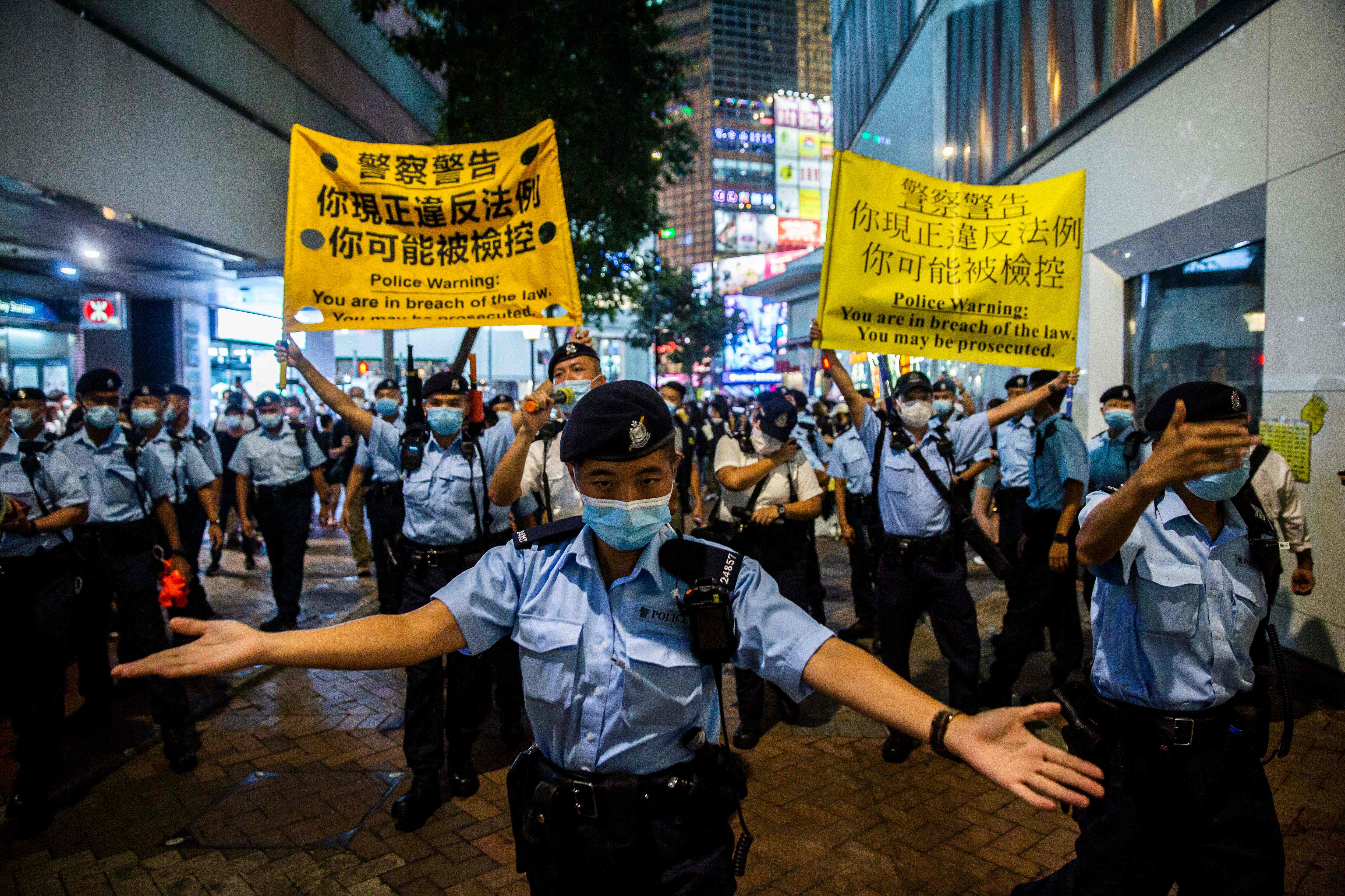 Police move people on as they gathered in the Causeway Bay district of Hong Kong on June 4, 2021, after police closed the venue where Hong Kong people traditionally gather annually to mourn the victims of China's Tiananmen Square crackdown in 1989 which the authorities have banned citing the coronavirus pandemic and vowed to stamp out any protests on the anniversary. (Photo by ISAAC LAWRENCE / AFP)