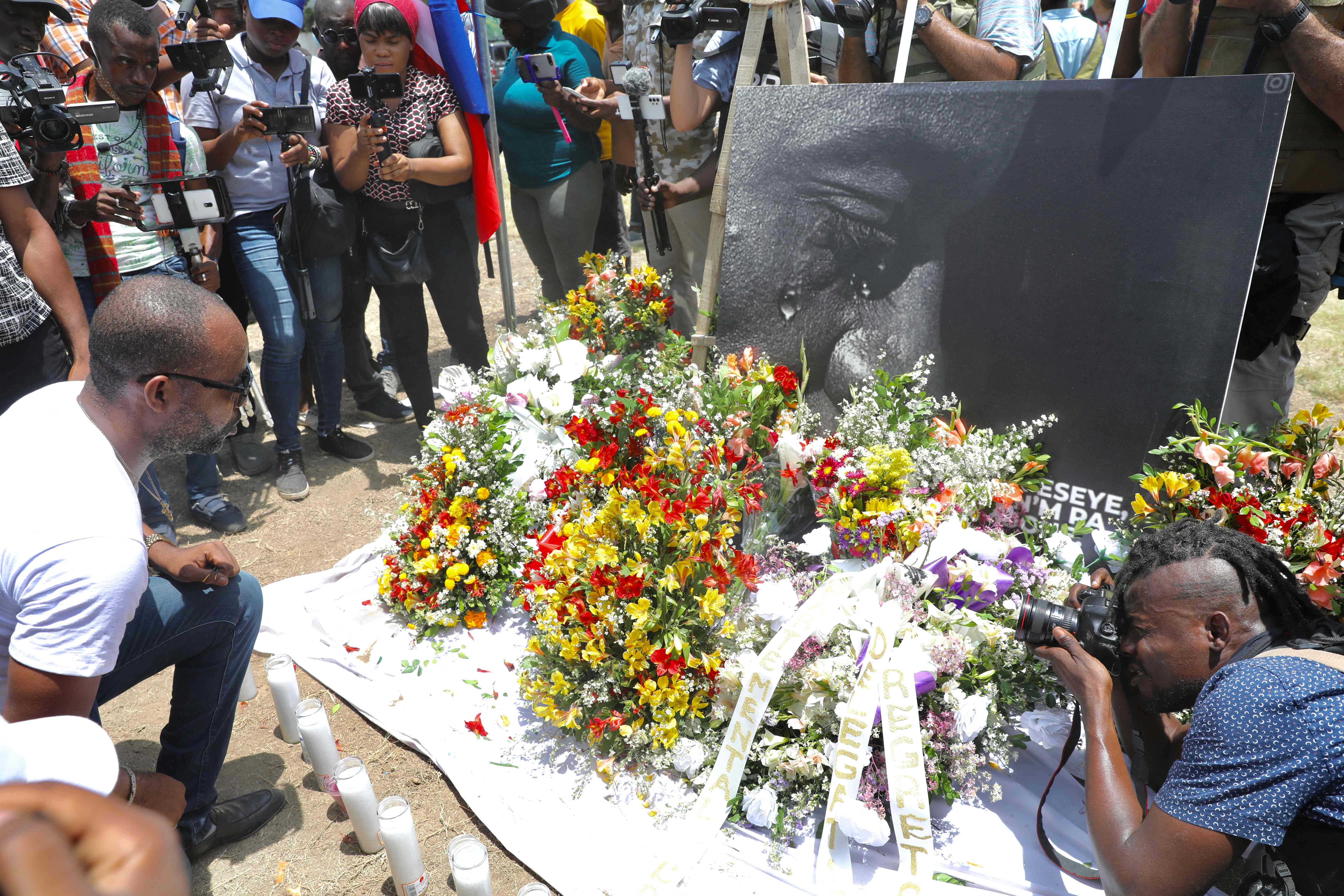 TOPSHOT - People pay their respects outside of the Presidential Palace in Port-au-Prince on July 14, 2021, in the wake of Haitian President Jovenel Moise's assassination that occurred early on July 7, 2021. - White House Press Secretary Jen Psaki said July 12, 2021 that the delegation of US law enforcement and national security officials who visited Haiti the previous day noted the country's instability in the wake of Moise's murder. She said Haiti's request for US troops to deploy and provide security was "still under analysis." Asked if the White House had ruled out sending troops, she said "no." No motive is publicly known for the killing, and questions are swirling about who masterminded the assassination. The delegation also met with Haitian political leaders, including interim Prime Minister Claude Joseph and Senate President Joseph Lambert, "to encourage open and constructive dialogue to reach a political accord that can enable the country to hold free and fair elections." (Photo by Valerie Baeriswyl / AFP)