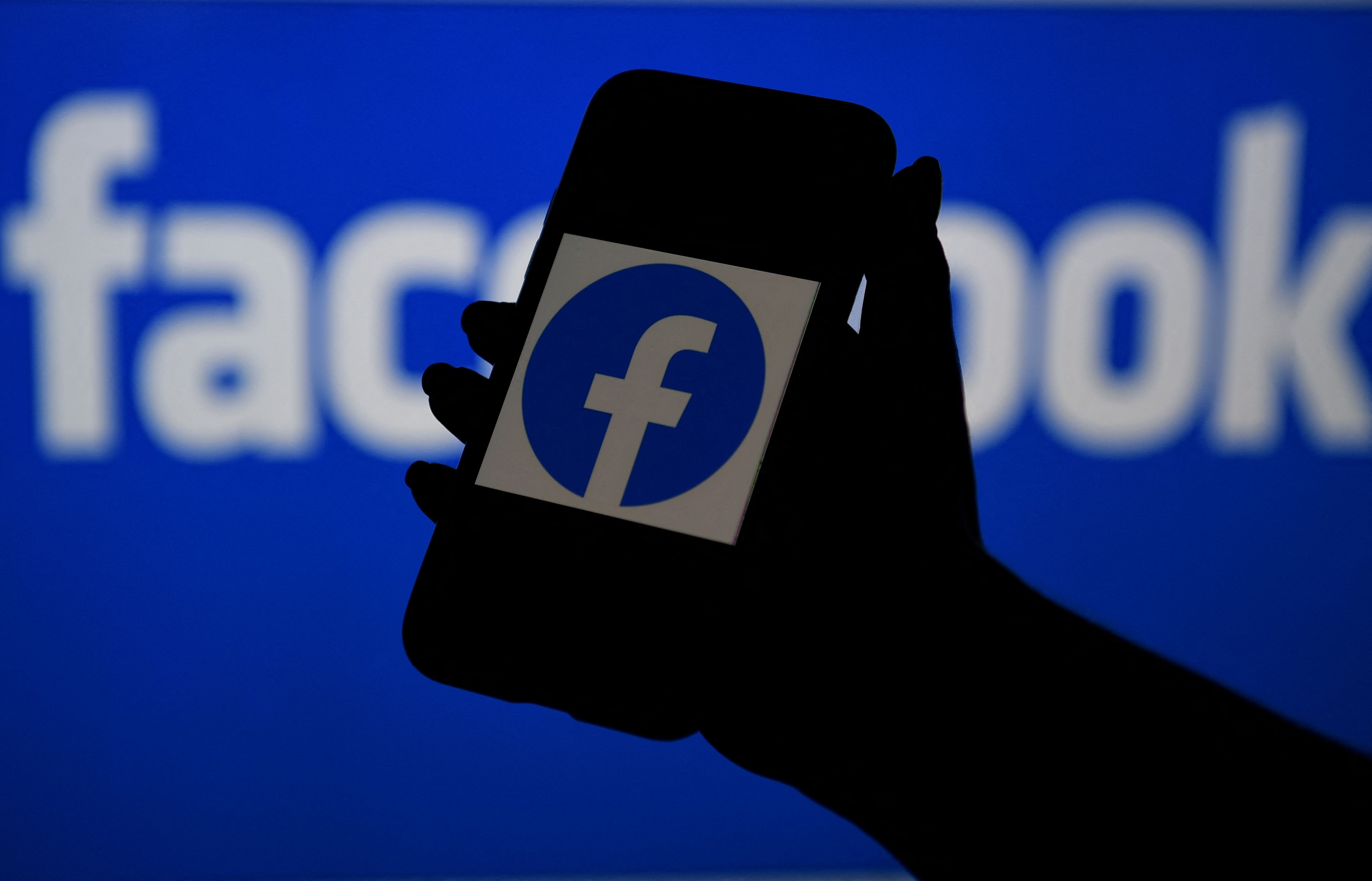 (FILES) In this file photo illustration, a smart phone screen displays the logo of Facebook on a Facebook website background, on April 7, 2021, in Arlington, Virginia - Facebook's independent Oversight Board announced on April 13, 2021 it would start accepting requests to remove "harmful content" that users believe has been wrongly allowed to remain on the leading social network. The move broadens the mandate of the so-called "supreme court" of Facebook, which up to now had been tasked with reviewing instances of whether content was improperly taken down from Facebook or Instagram. (Photo by OLIVIER DOULIERY / AFP)