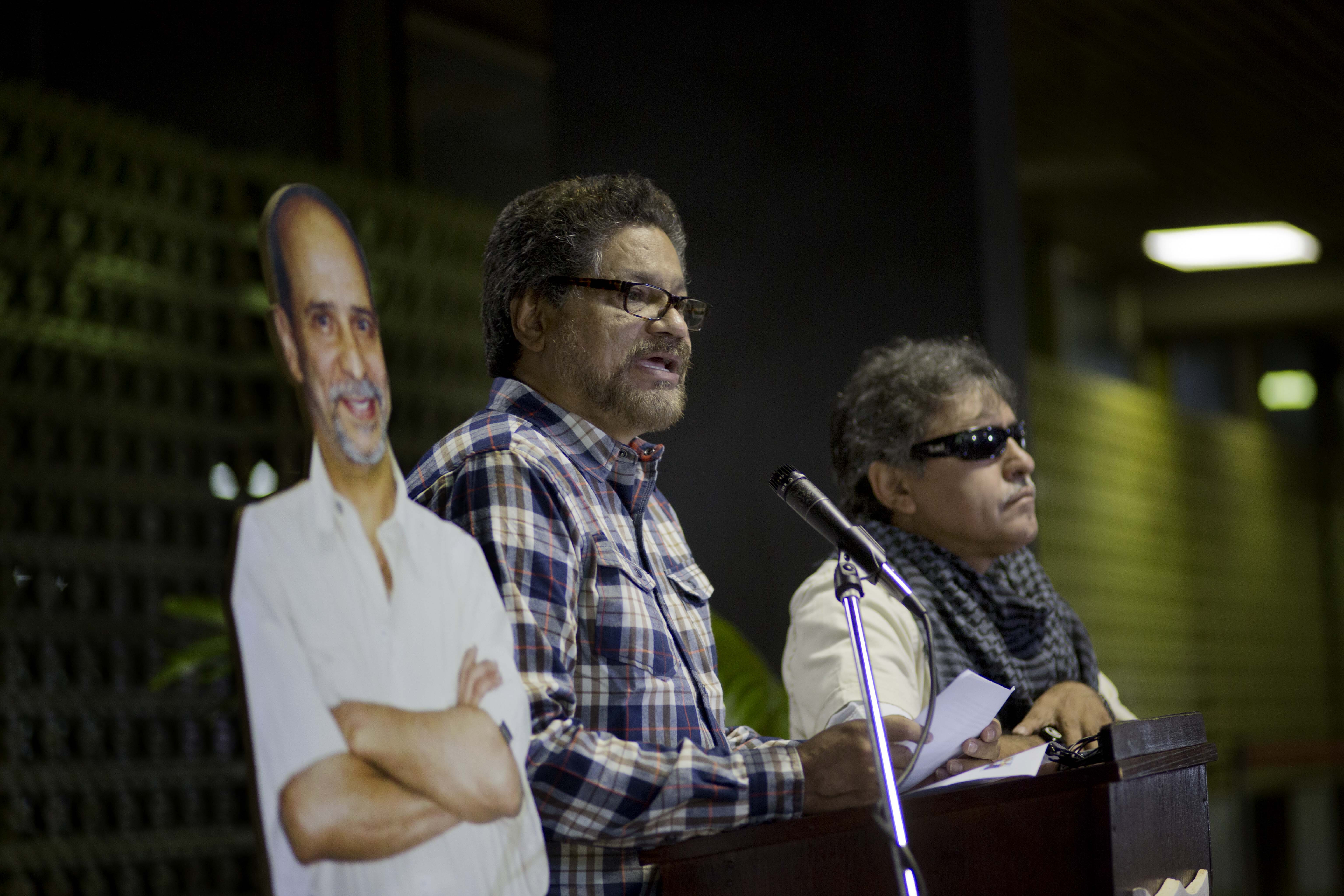 FILE - In this Sept. 23, 2014 file photo, Ivan Marquez, chief negotiator for the Revolutionary Armed Forces of Colombia, FARC, flanked by a life-size cut out image of rebel commander Jaime Palmera, alias "Simon Trinidad", who's serving time in a U.S. federal prison, and Jesus Santrich, right, speaks to journalists after arriving for the start of a new round of peace talks with Colombia's government peace negotiation team in Havana, Cuba. The top peace negotiator for the FARC announced Thursday,Aug. 29, 2019, that he and a cadre of hardline supporters are taking up arms again, accusing President Ivan Duque of failing to uphold the accord that sought to end a half century of bloody fighting. (AP Photo/Ramon Espinosa, File)