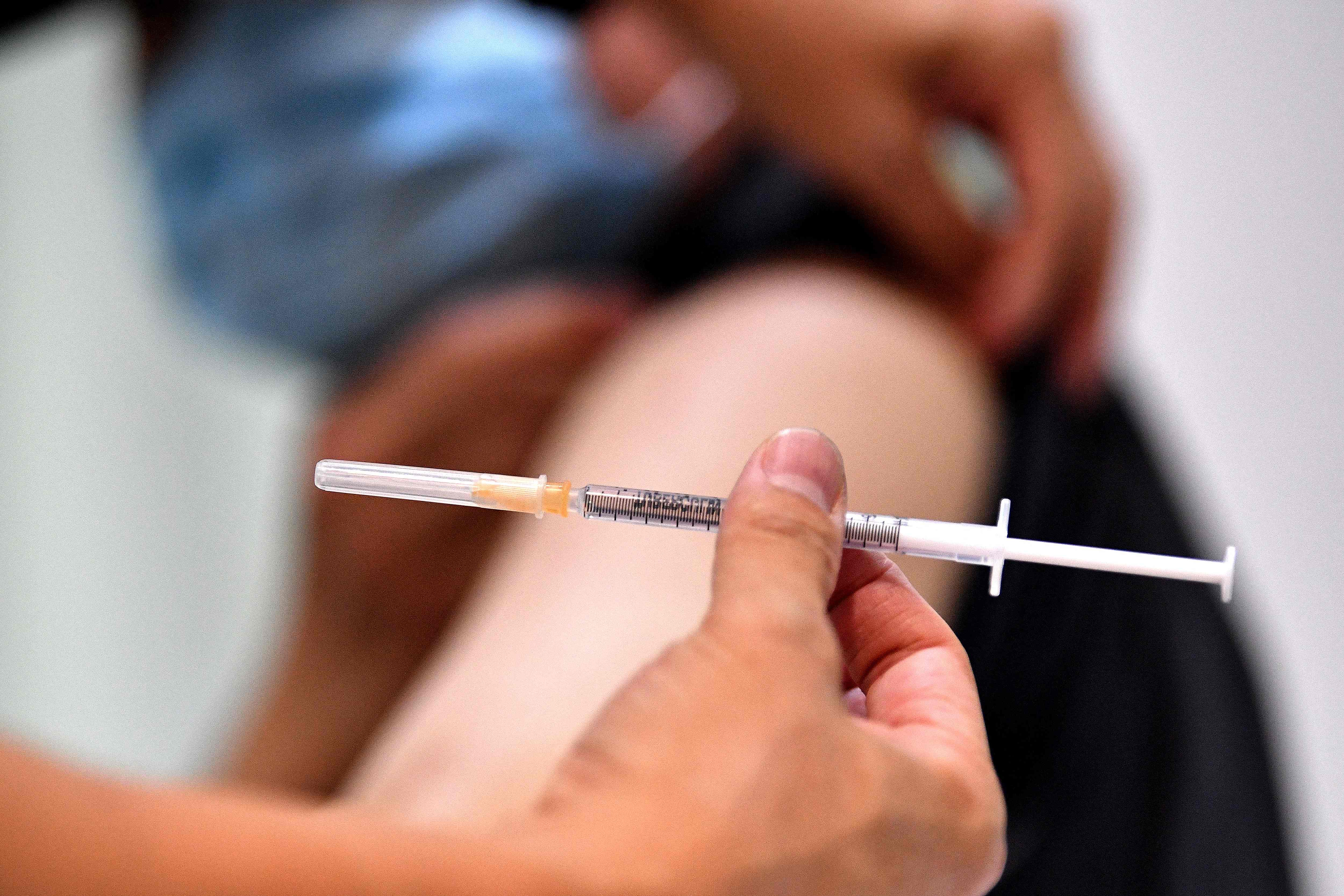 A resident receives his first dose of the AstraZeneca vaccine at a walk-in Covid-19 vaccination centre inside a pharmacy in the suburb of Cabramatta in Sydney on August 17, 2021. (Photo by Saeed KHAN / AFP)