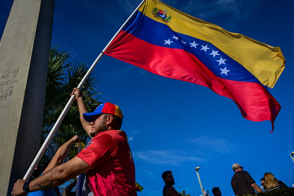 People react to the news of the capture of Venezuelan President Nicolas Maduro, after US military actions in Venezuela this morning, in Doral, Florida, near Miami, on January 3, 2026. Venezuelan President Nicolas Maduro arrived Saturday evening at a military base in the United States after his capture by US forces in Caracas. Maduro was seen surrounded by FBI agents as he descended the boarding stairs of a US government plane at a New York state National Guard facility, and was slowly escorted along the tarmac. (Photo by GIORGIO VIERA / AFP)