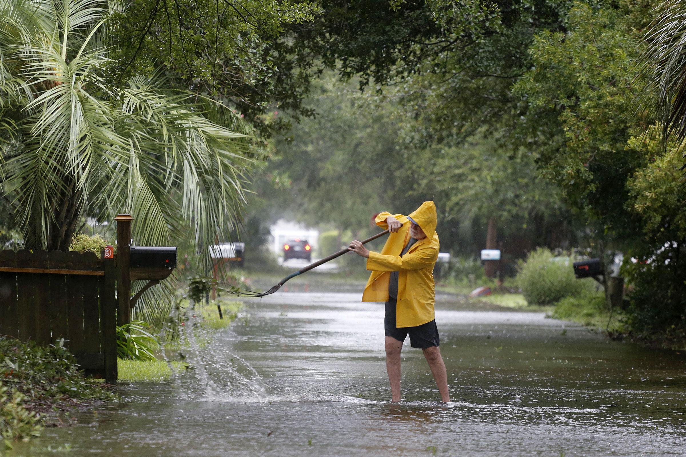 An Isle of Palms resident clears the drain on Hartnett Blvd. during Hurricane Dorian at the Isle of Palms, S.C., Thursday, Sept. 5, 2019, in Charleston, S.C. (AP Photo/Mic Smith)