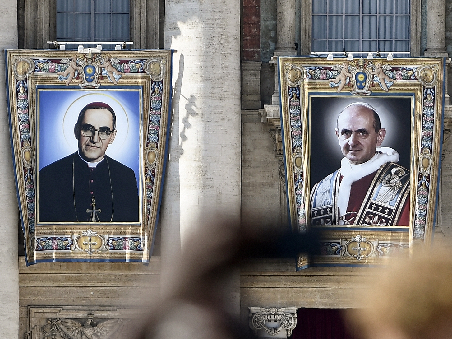 Los tapices del arzobispo católico Oscar Romero (L) y el Papa Pablo VI cuelgan de un balcón de la fachada de la Basílica de San Pedro en el Vaticano el 13 de octubre de 2018. El Papa Francisco presidirá el 14 de octubre de 2018 sobre la misa de canonización para el Papa. Pablo VI y el arzobispo salvadoreño asesinado Oscar Romero. AFP