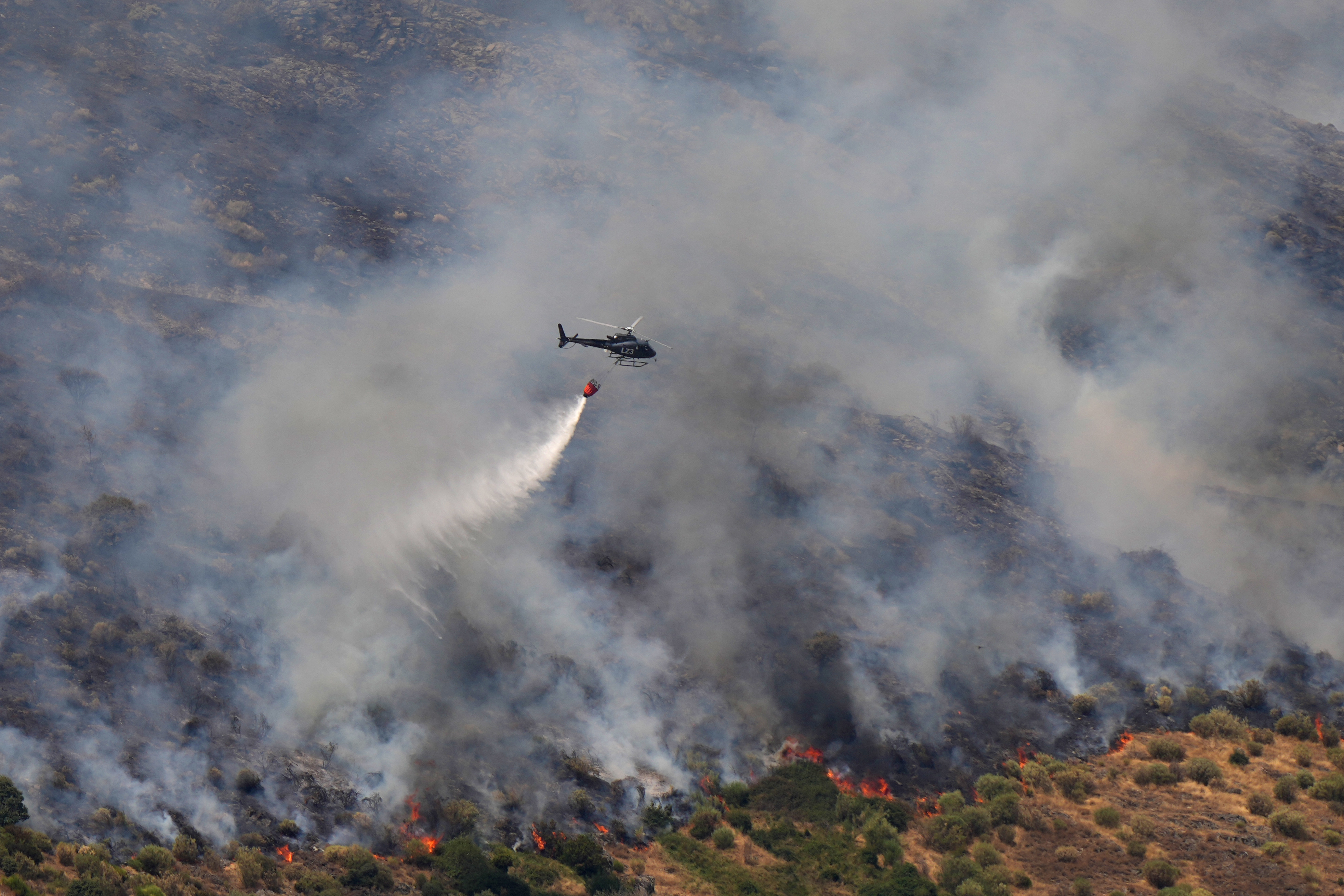 A helicopter fights a wildfire in Castrillo de Cabrera, northwestern Spain, on August 16, 2025. Spain, now in its third week under a heatwave alert, is still battling wildfires raging in the northwest and west of the country, where the army has been deployed to help contain the blazes. The regions of Castilla y Leon, Galicia, Asturias and Extr