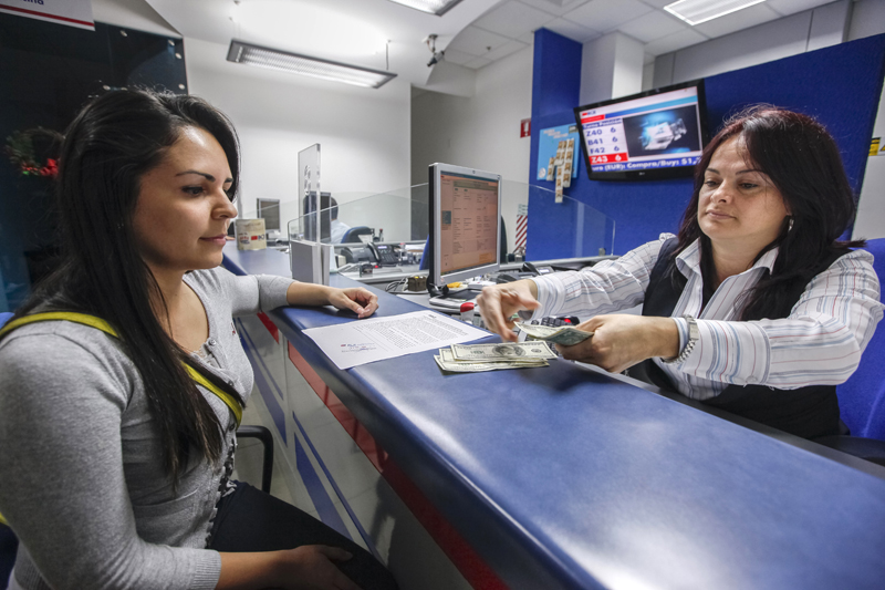 Paola Villalobos es atendida por la plataformista Hellen Sánchez. En las ventanillas de las entidades financieras las compras de divisas de las entidades al público volvieron a superar a las ventas.