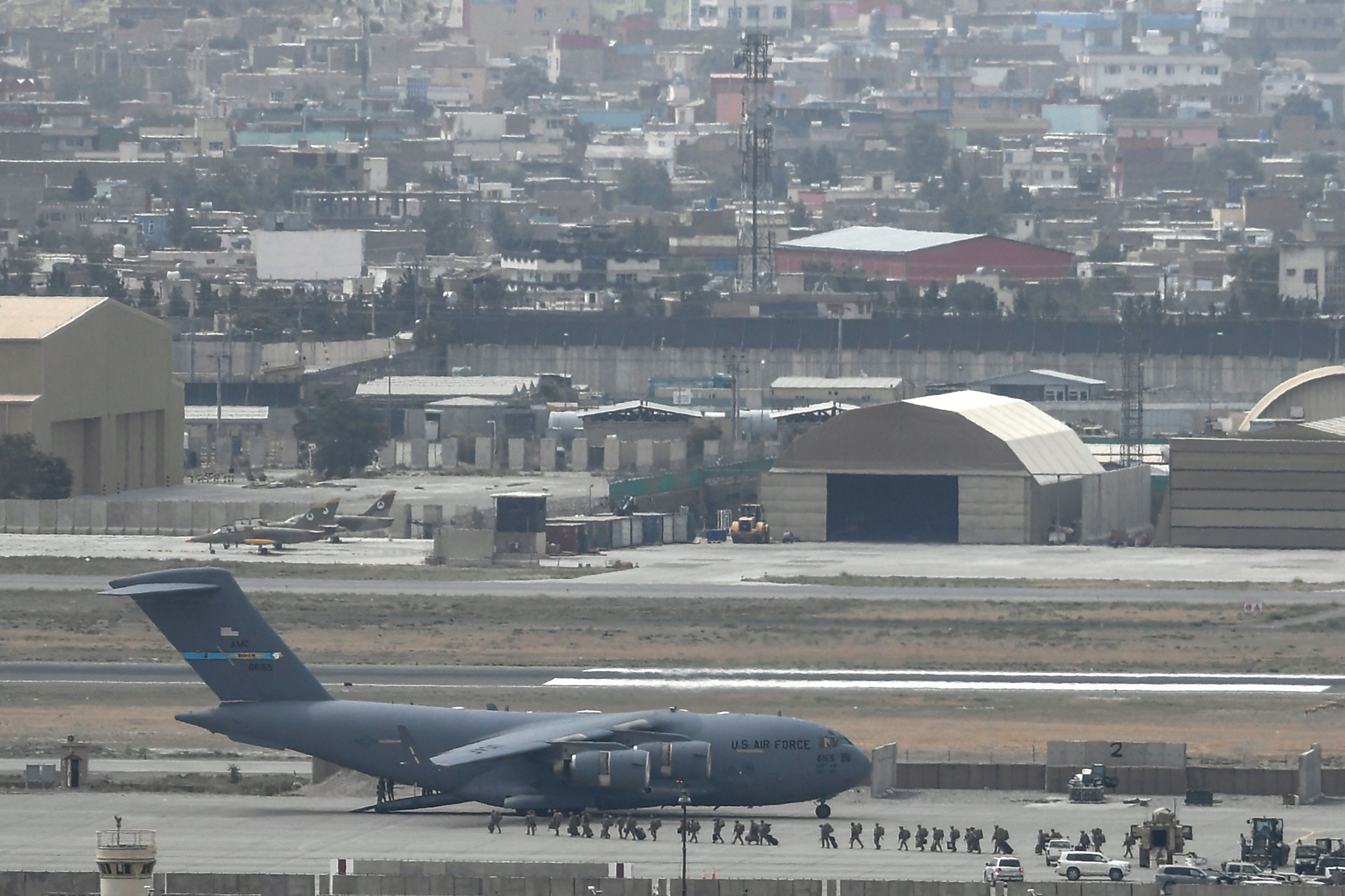 US soldiers arrive board an US Air Force aircraft at the airport in Kabul on August 30, 2021. - Rockets were fired at Kabul's airport on August 30 where US troops were racing to complete their withdrawal from Afghanistan and evacuate allies under the threat of Islamic State group attacks. (Photo by Aamir QURESHI / AFP)