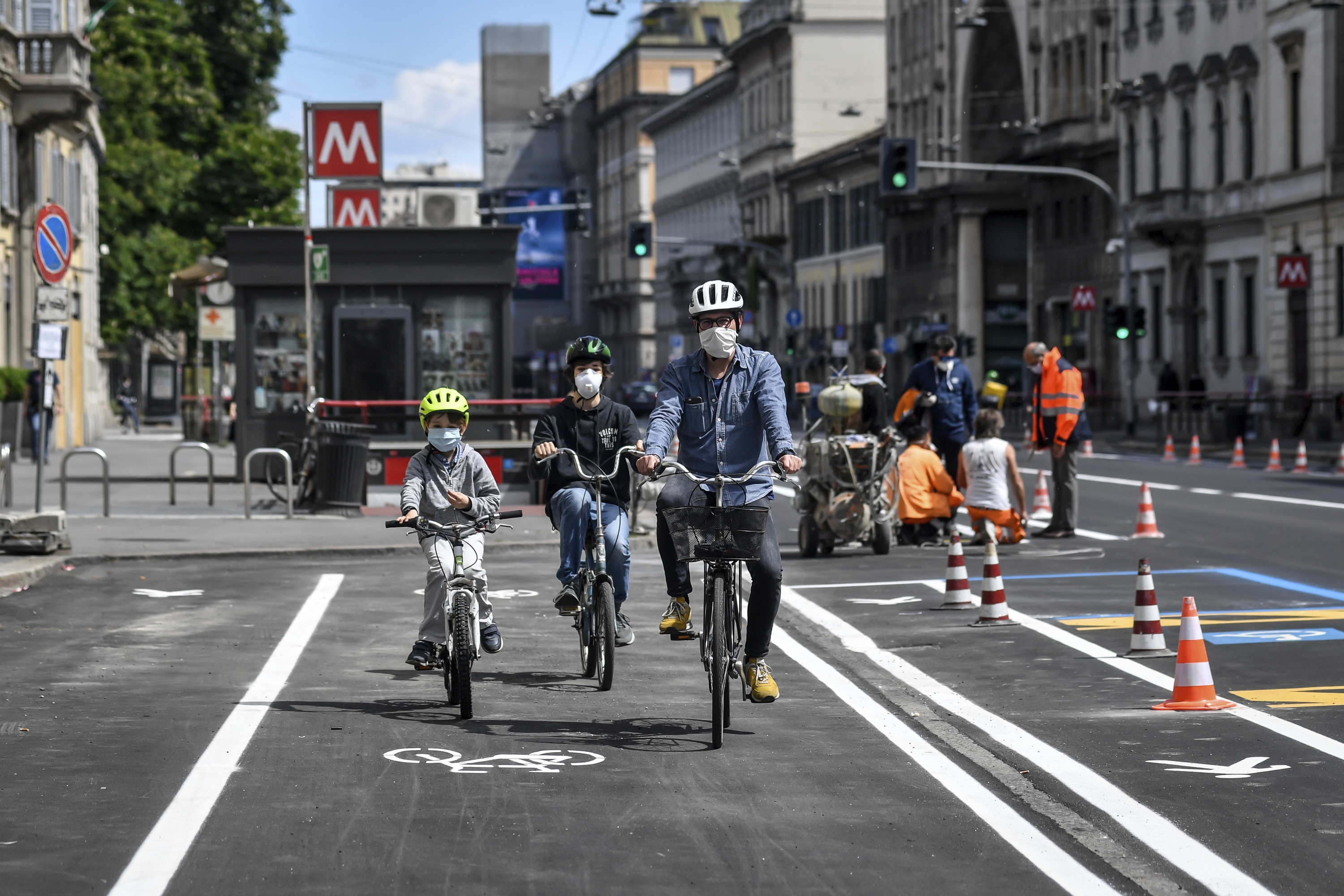 A family tries the new cycle path being prepared in central Milan's Corso Venezia, Italy, in view of Monday's partial reopening of activities, with a reduced capacity of public transportation due to safety measures against coronavirus, Saturday, May 2, 2020. Italians are preparing for the so called "phase 2" Monday, that will see a partial reopening of many activities after two months of lockdown due to the coronavirus outbreak. (Claudio Furlan/LaPresse via AP)
