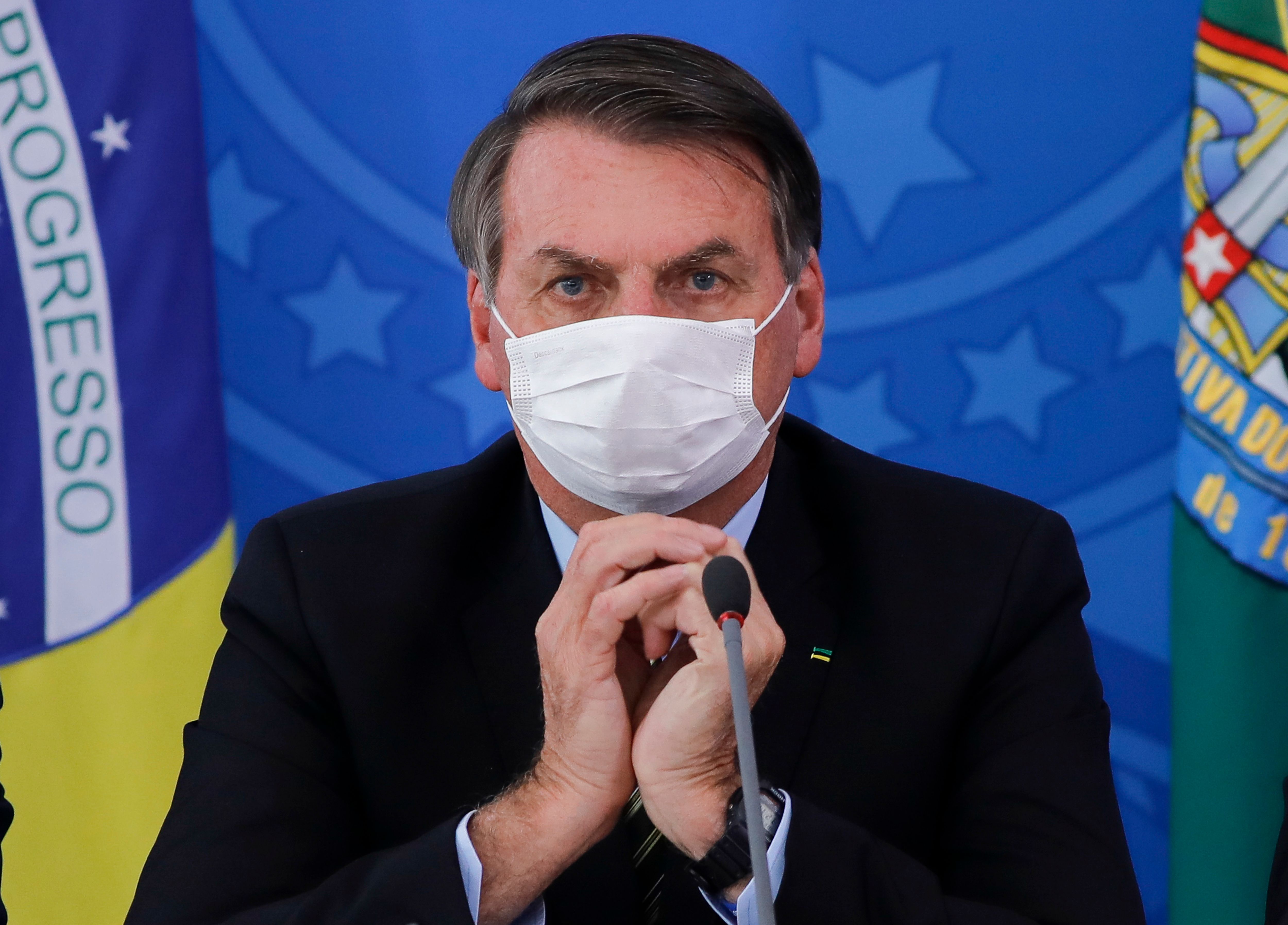 TOPSHOT - Brazilian President Jair Bolsonaro gestures using a face cover during a press conference regarding the COVID-19, coronavirus pandemic at the Planalto Palace, Brasilia on March 18, 2020. (Photo by Sergio LIMA / AFP)