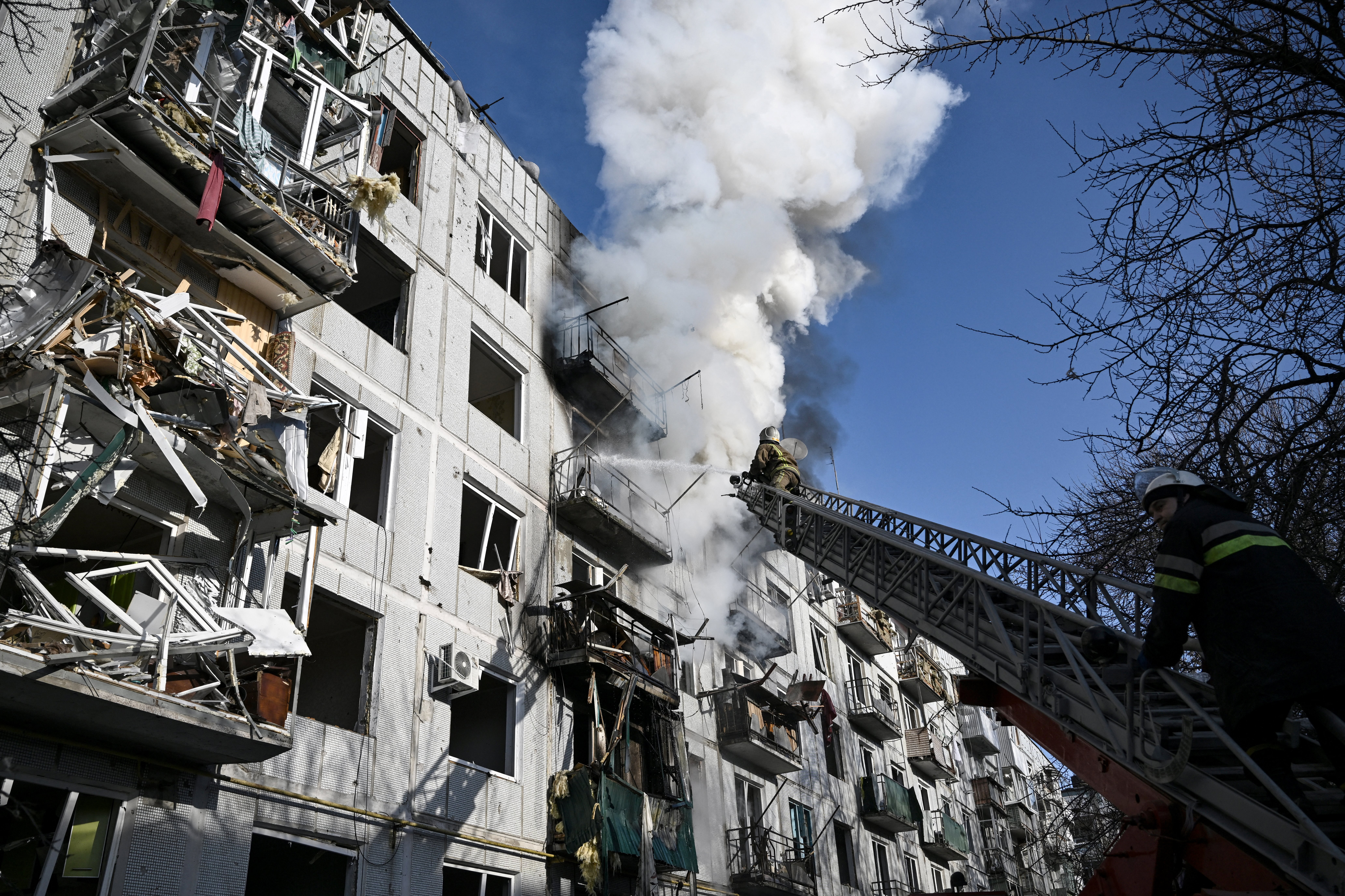 Los bomberos trabajan en un incendio en un edificio después de los bombardeos en la ciudad de Chuguiv, en el este de Ucrania, (Foto de Aris Messinis / AFP)