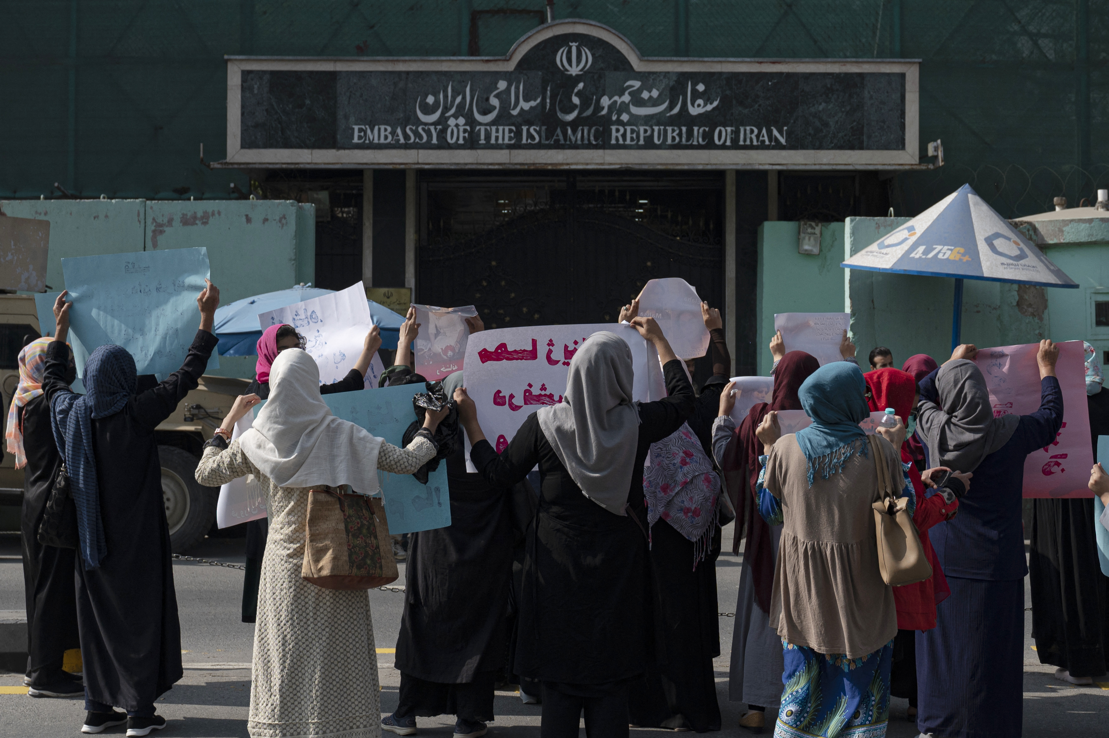 Afghan women hold placards as they take part in a protest in front of the Iranian embassy in Kabul on September 29, 2022. - Taliban forces fired shots into the air on September 29 to disperse a women's rally supporting protests that have erupted in Iran over the death of a woman in the custody of morality police. (Photo by Wakil KOHSAR / AFP)