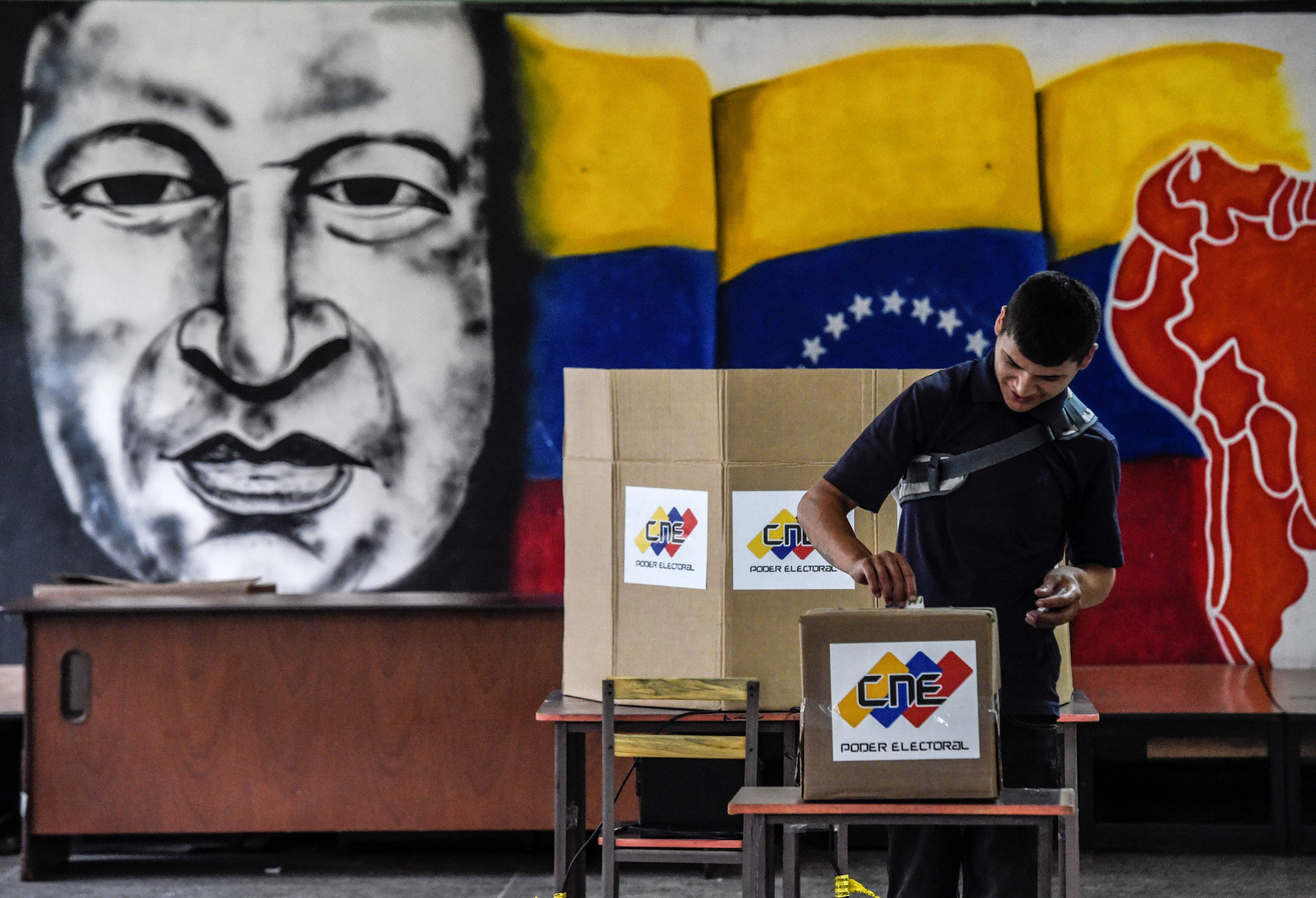 Un hombre da su voto frente a una imagen del fallecido presidente venezolano Hugo Chávez, durante las elecciones presidenciales en un colegio electoral en Caracas el 20 de mayo de 2018. AFP
