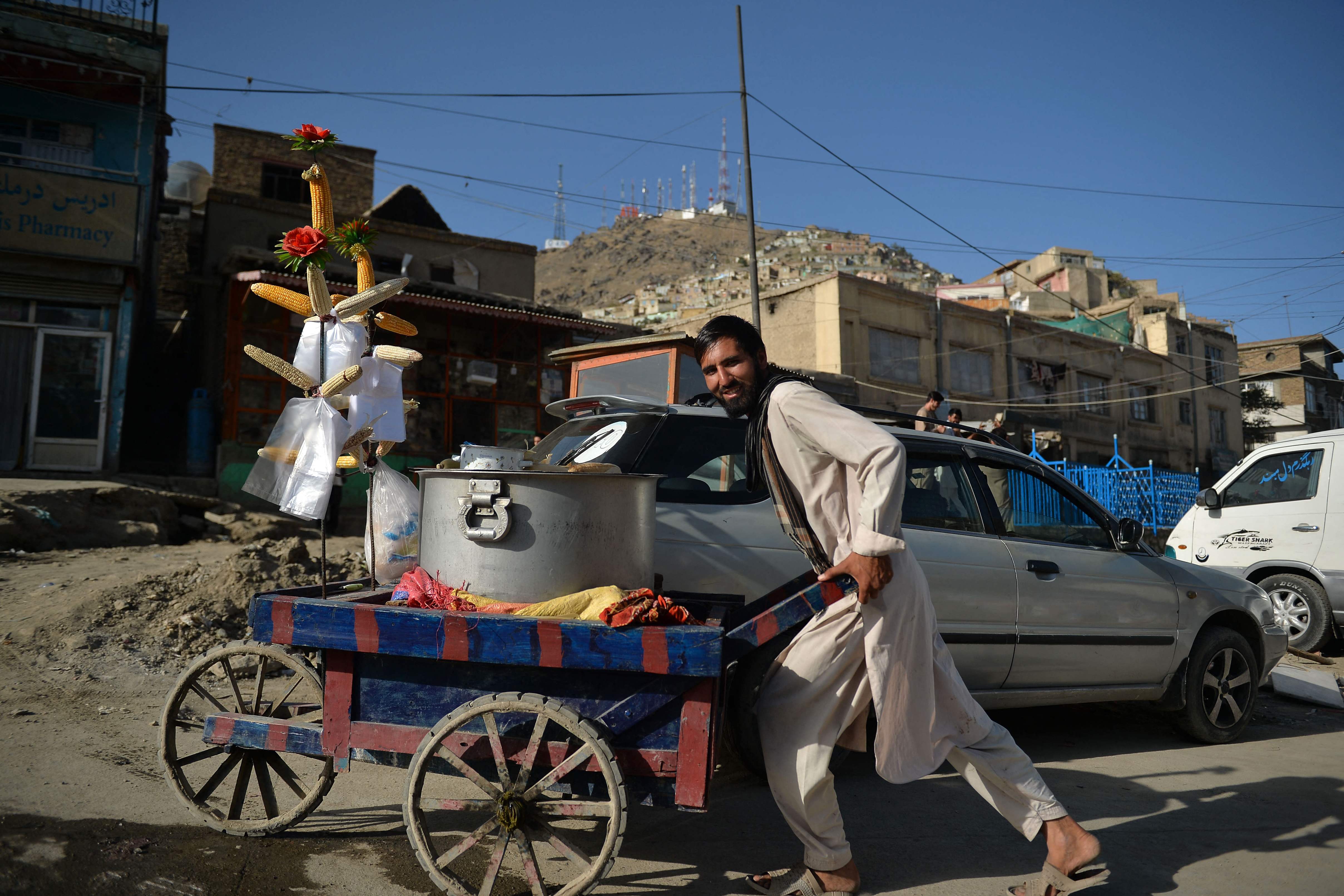 A vendor selling corns pushes his handcart along a street in Kabul on September 13, 2021. (Photo by Hoshang Hashimi / AFP)