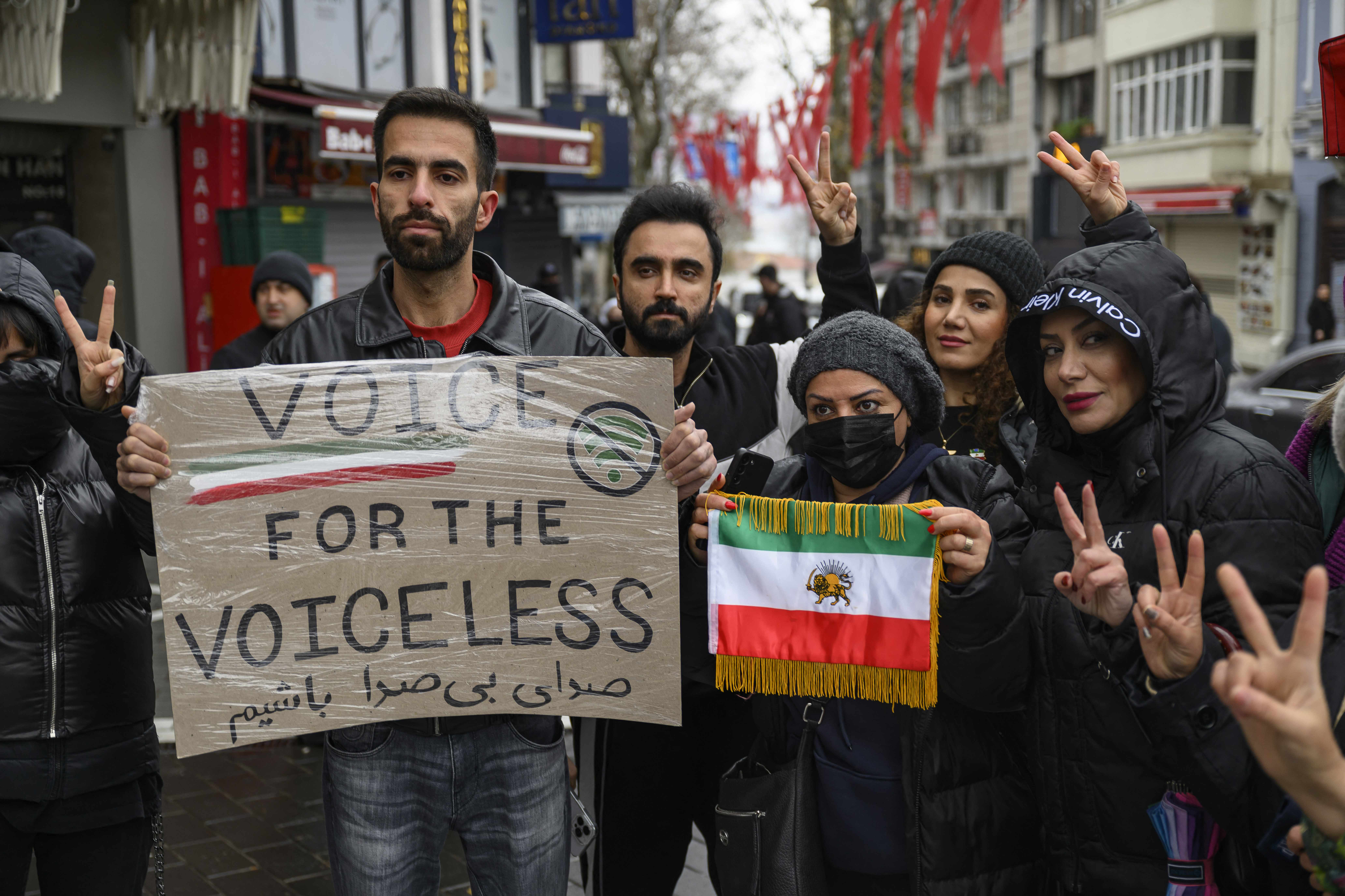 Anti-Iranian regime protesters hold a placard reading "Voice for the voiceless" and the flag of Iran from before the 1979 revolution, with the Lion and Sun emblems, during a demonstration outside the Iranian Consulate in Istanbul, on January 11, 2026. At least 192 protesters have been killed in Iran's biggest movement against the Islamic republic in more than three years, a rights group said on January 11, 2026 as warnings grew that authorities were committing a "massacre" to quell the demonstrations (Photo by Yasin AKGUL / AFP)