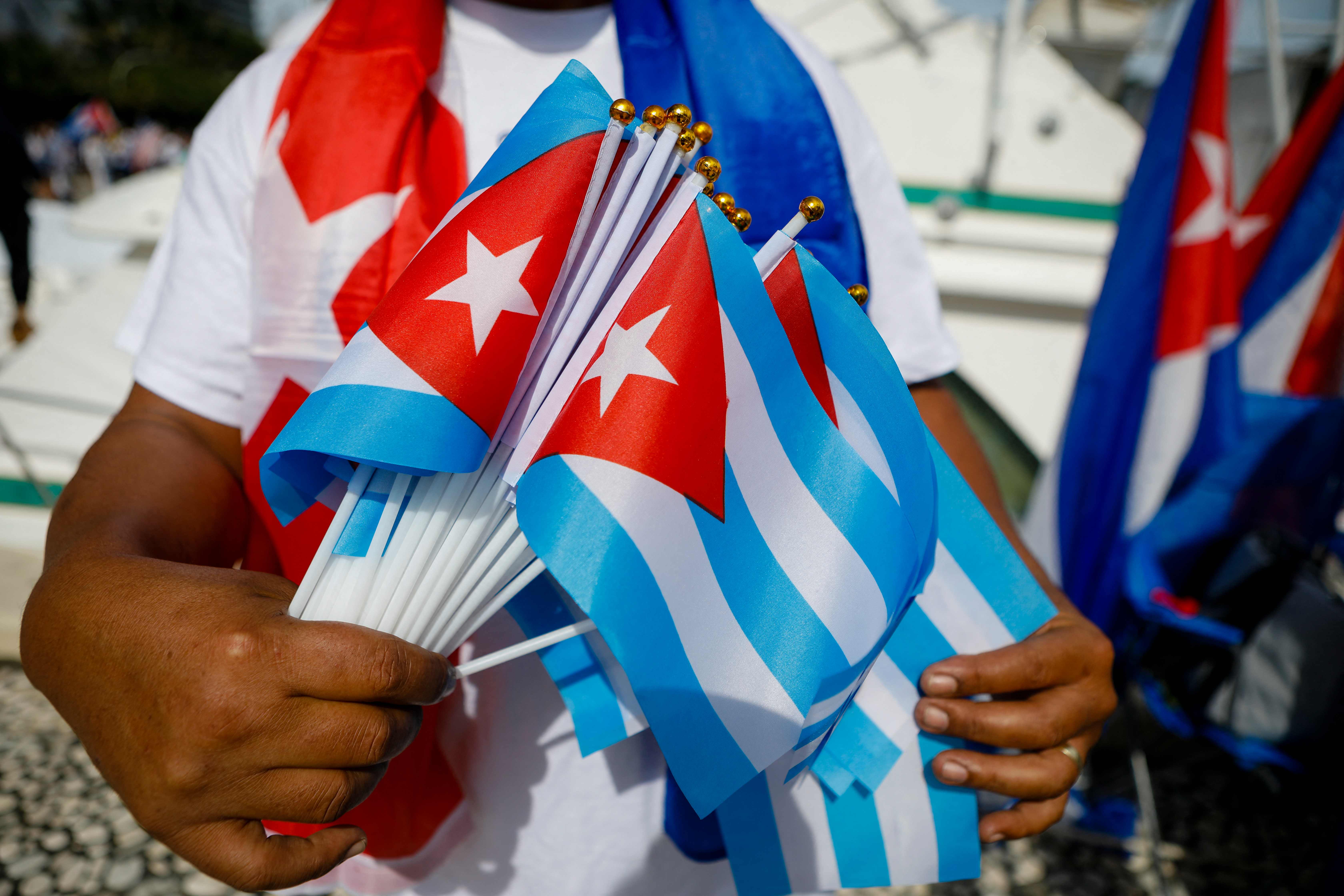 A demonstrator hands out Cuban flags during a rally in Miami to support Cuban anti-government protesters, on November 14, 2021. - The US urged Cuban authorities on Sunday to lift a ban on protests ahead of planned anti-government demonstrations, the State Department said in a statement. Cuba's opposition has called for demonstrations in Havana and six provinces on November 15, which have been prohibited by the communist authorities, to call for the release of political prisoners. (Photo by Eva Marie UZCATEGUI / AFP)