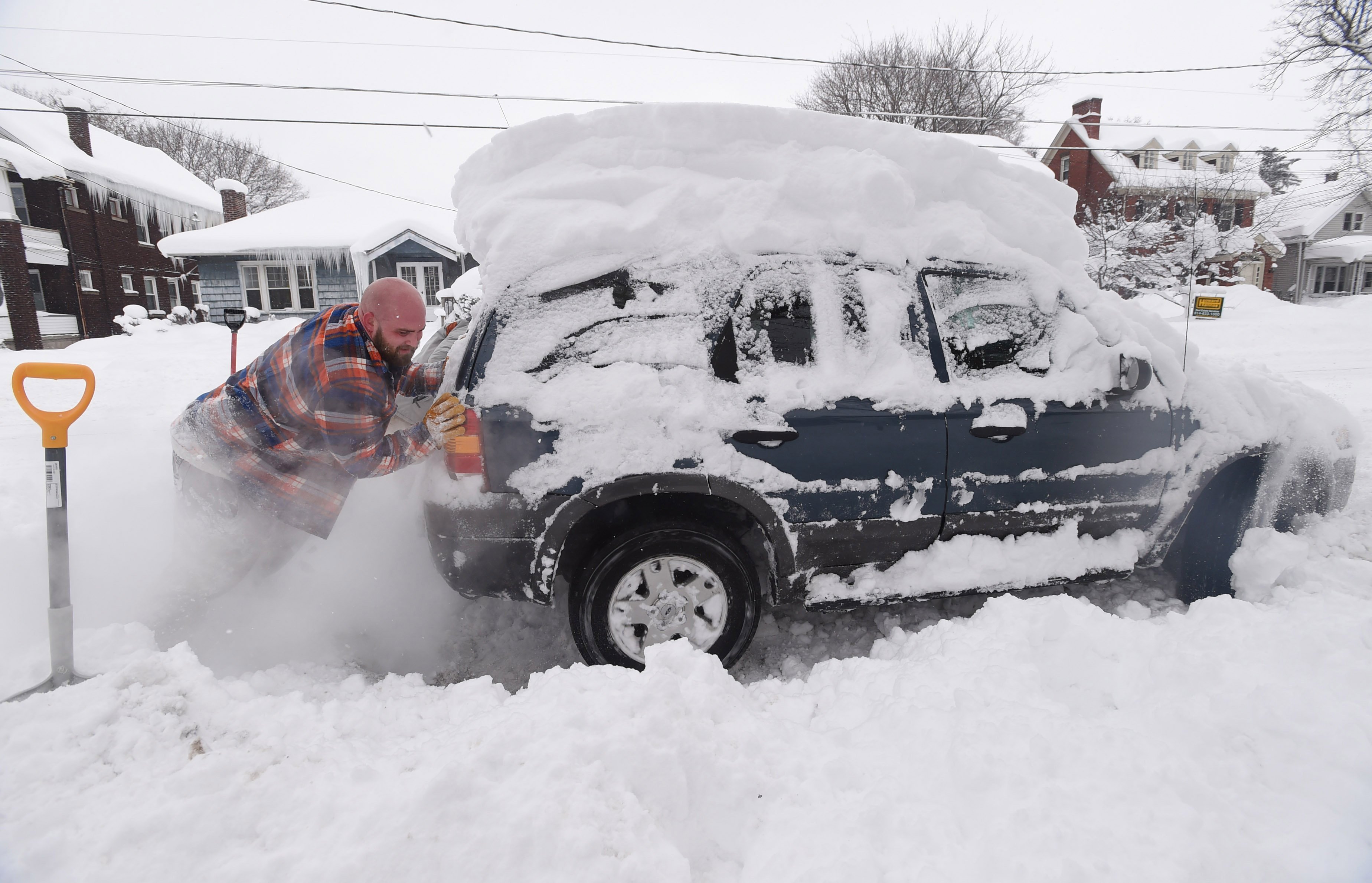 Kevin Deiner of Erie, Pa., pushes his Ford Escape out of the deep snow on West Sixth Street Saturday, Dec. 30, 2017. Forecasters say 1 to 3 inches of snow could fall in most areas before the precipitation end by late Saturday afternoon. But several inches of snow were expected in Erie, which was under a lake effect snow warning issued by the National Weather Service. ( Jack Hanrahan/Erie Times-News via AP)