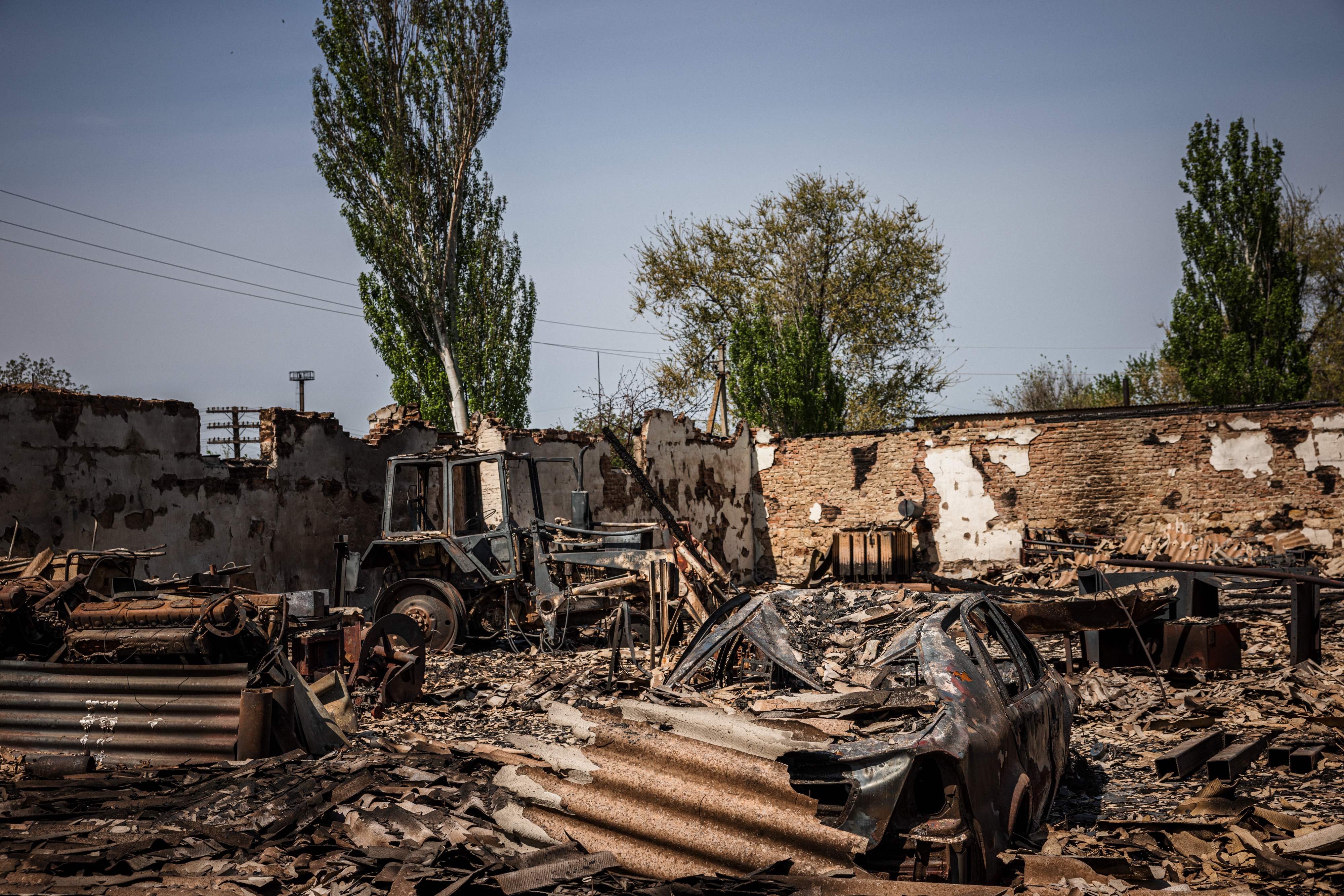 This picture taken on May 11, 2022, shows burnt car and tractor after shelling by Russian forces in the town of Orikhiv, near Zaporizhzhia, eastern Ukraine, amid the Russian invasion. (Photo by Dimitar DILKOFF / AFP)