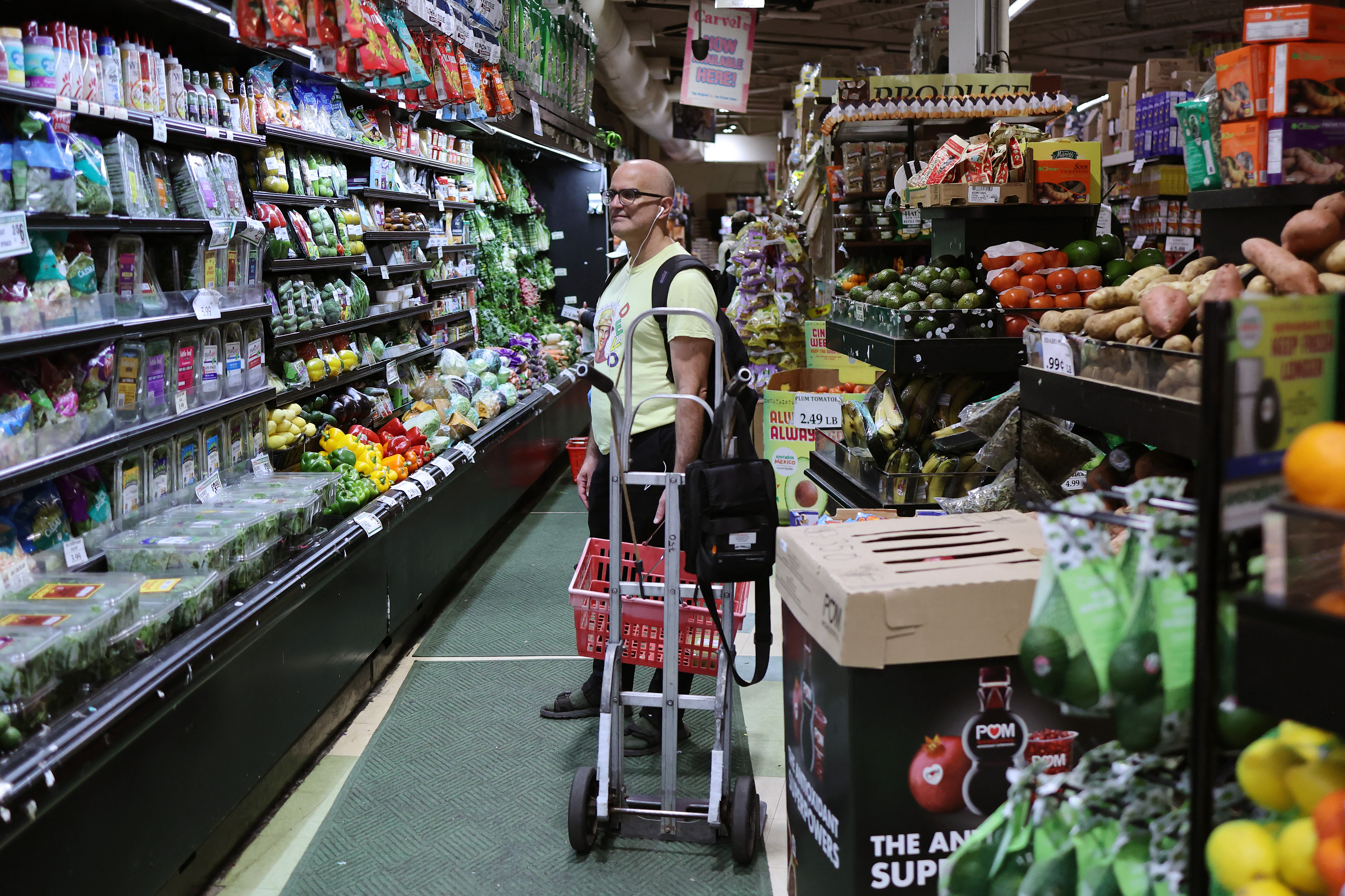 Un hombre con carrito de compras inspecciona productos frescos en un pasillo de supermercado en Estados Unidos, en el contexto de inflación y ajustes de tasas de interés por la Reserva Federal.