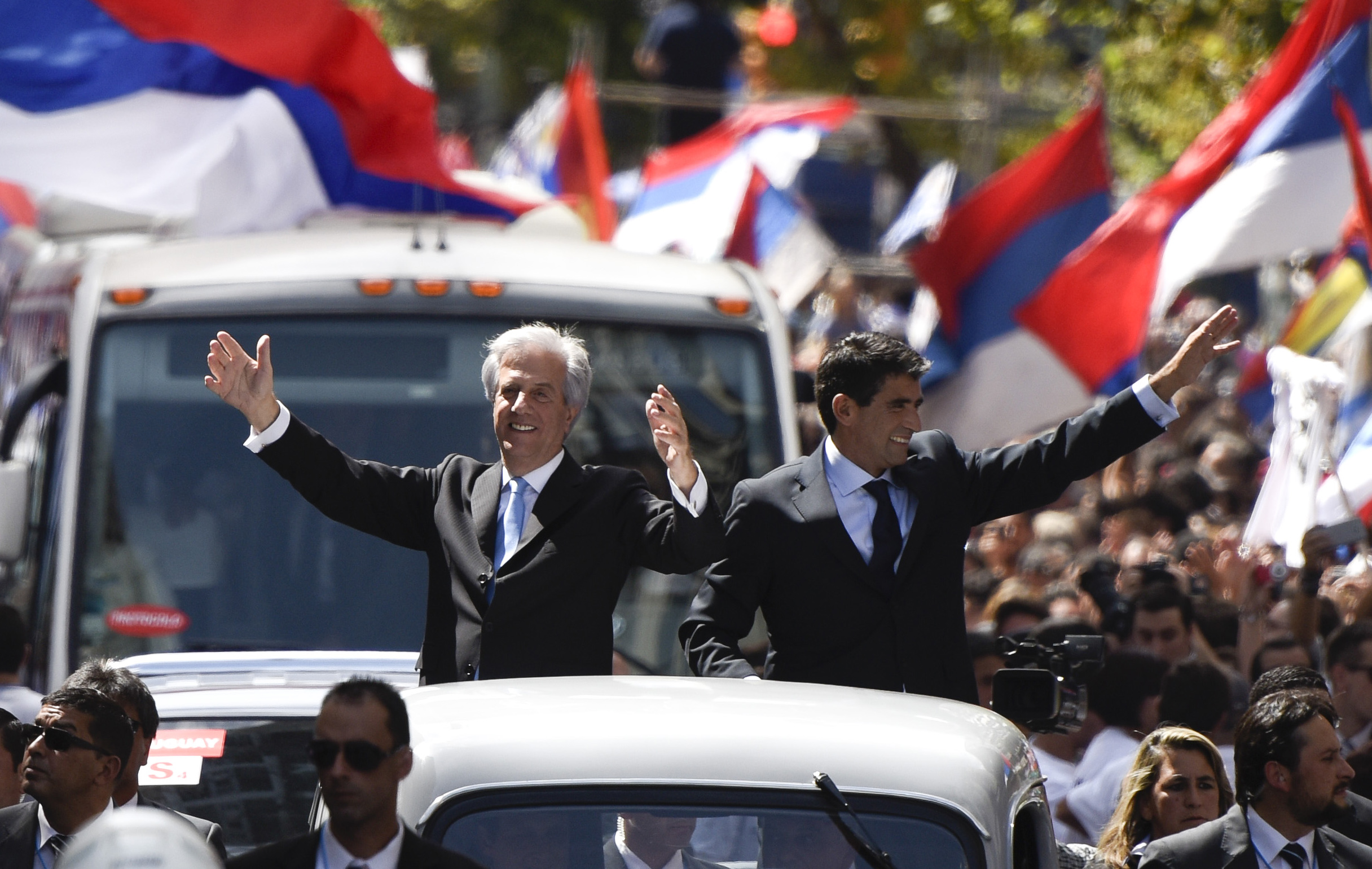 El nuevo presidente de Uruguay, Tabaré Vázquez, (izquierda), y su vicepresidente Raúl Sendic, saludan a la multitud desde la parte posterior de un vehículo después de su toma de posesión en Montevideo, Uruguay.